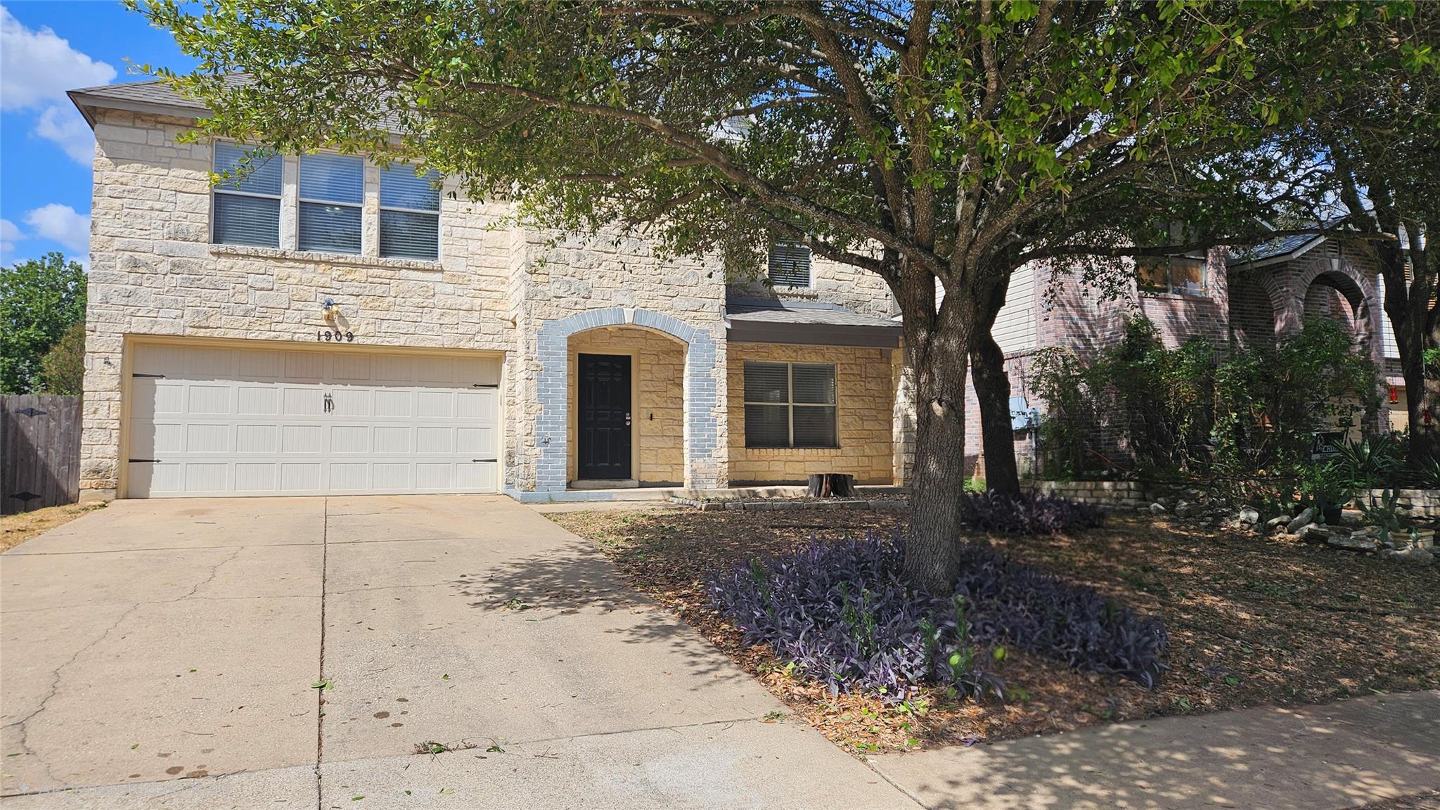 Textured stone siding and a wide concrete drivewa