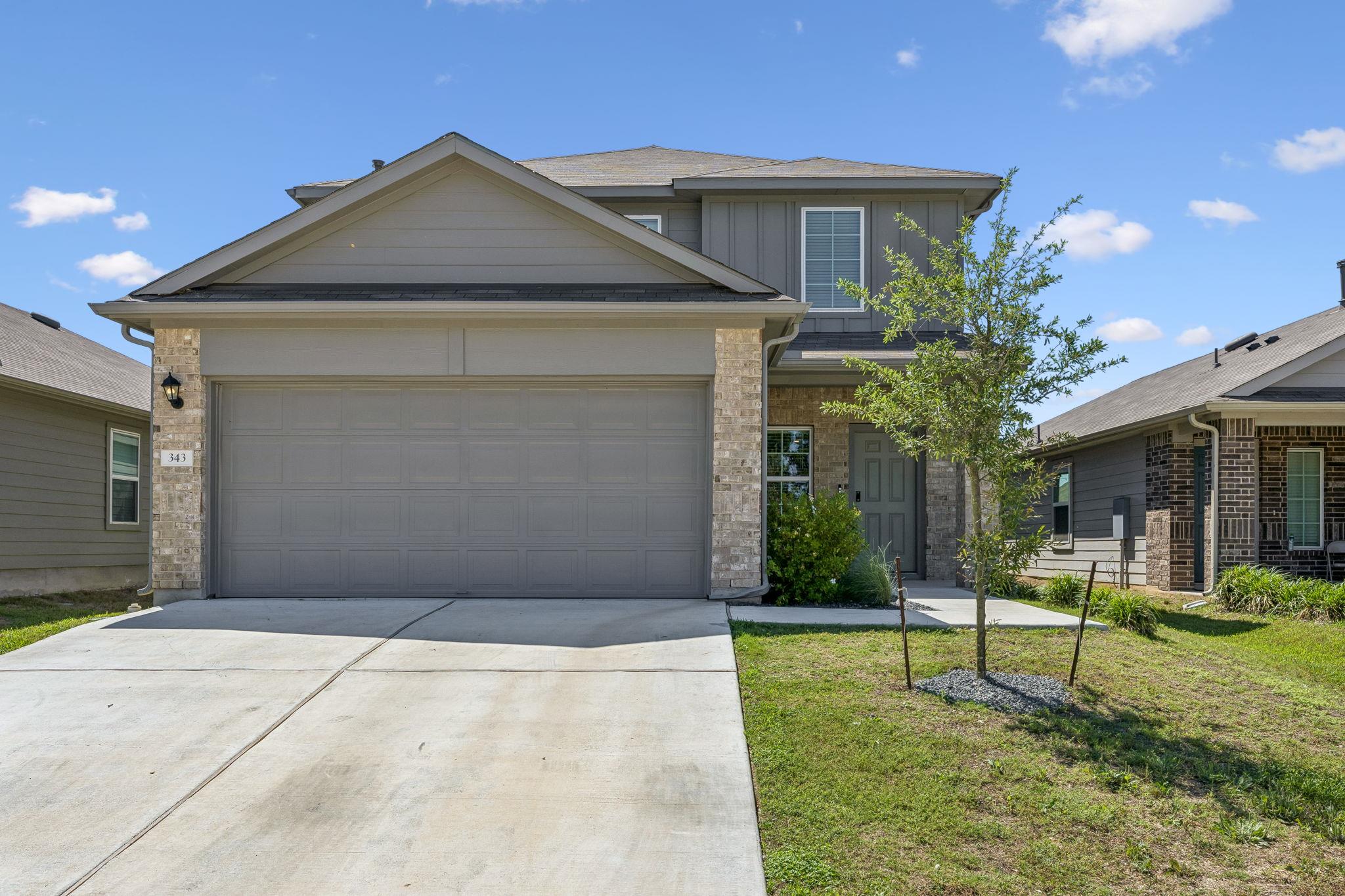 A spacious driveway and concrete path lead to thi