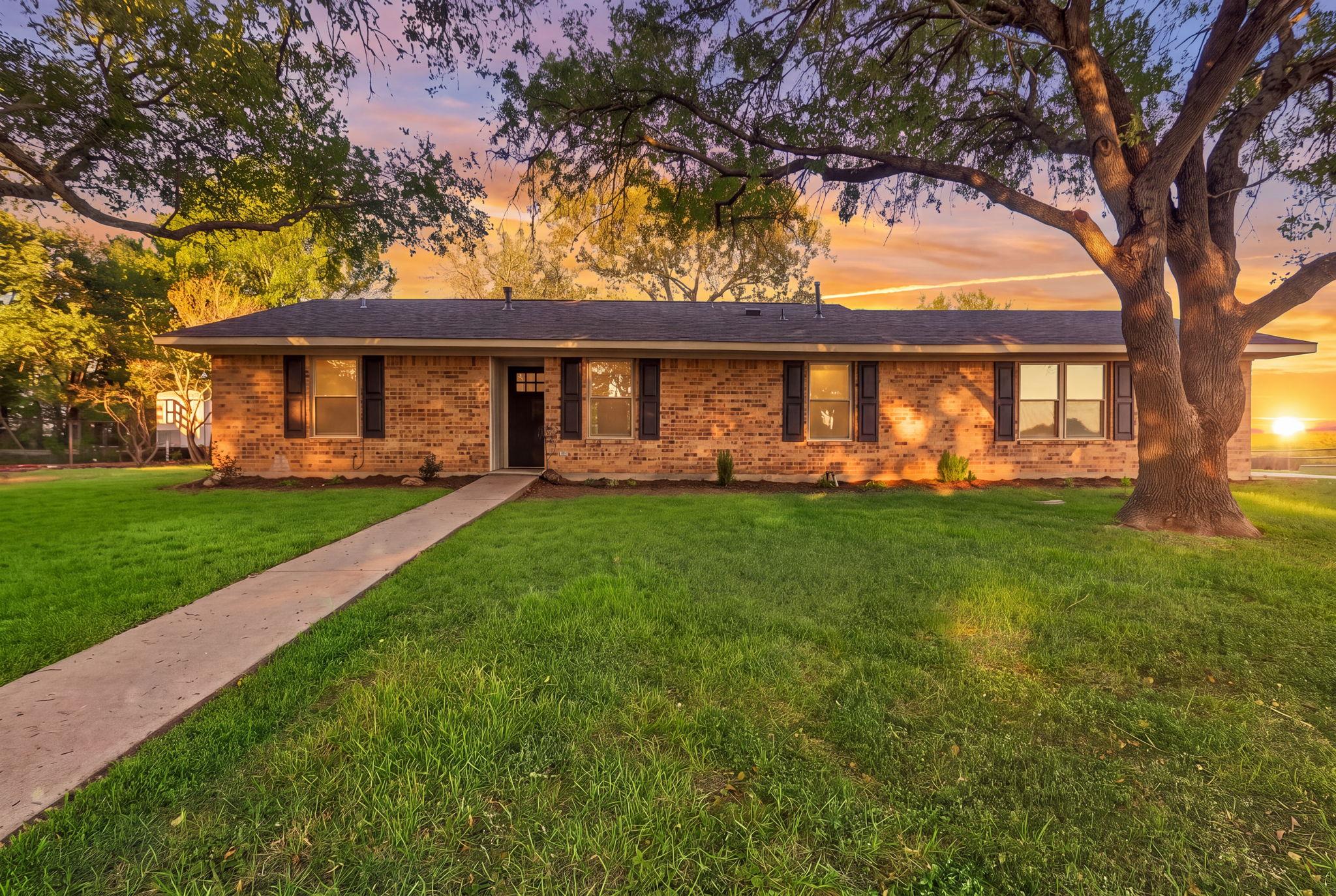 A classic brick exterior framed by mature trees p