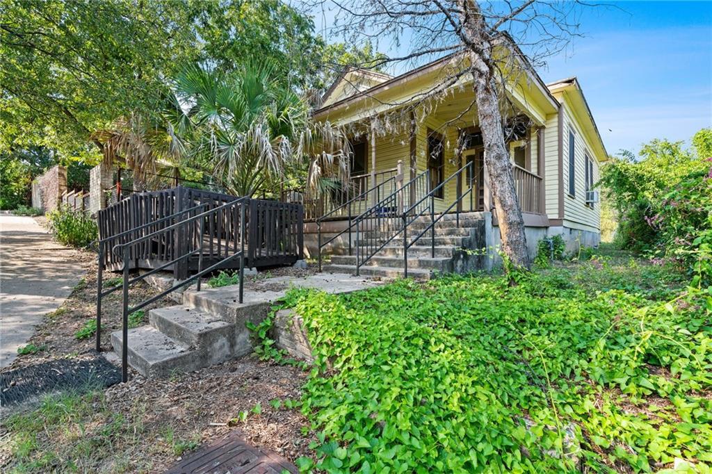 Concrete steps ascend to a classic front porch su