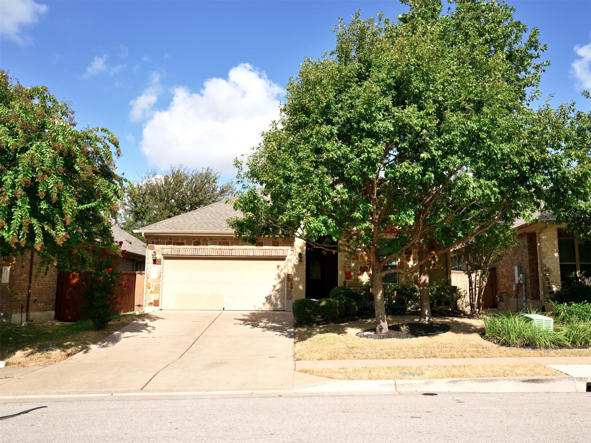 Mature trees frame a classic stone front facade w