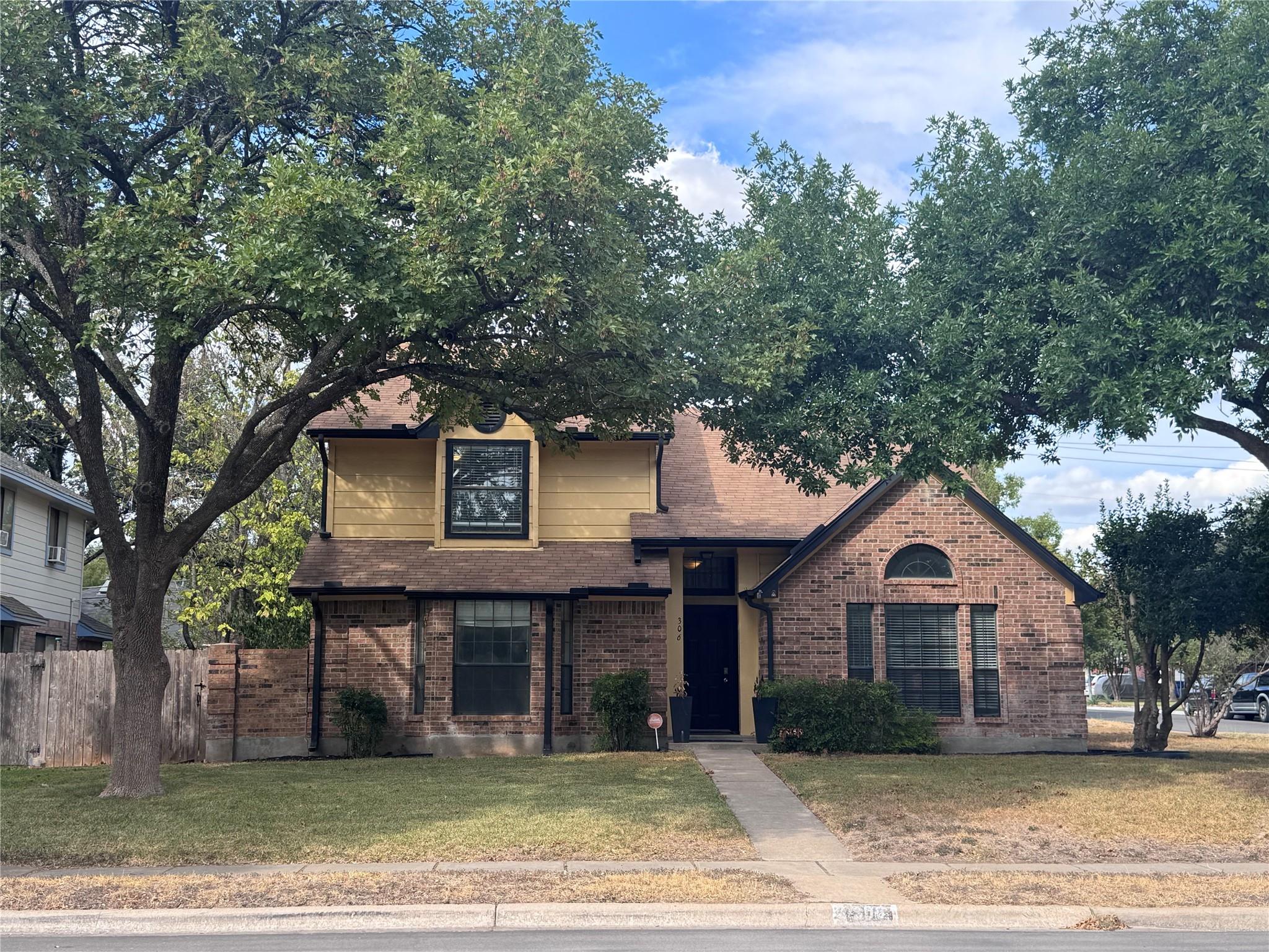 Mature trees frame a classic brick facade with a 