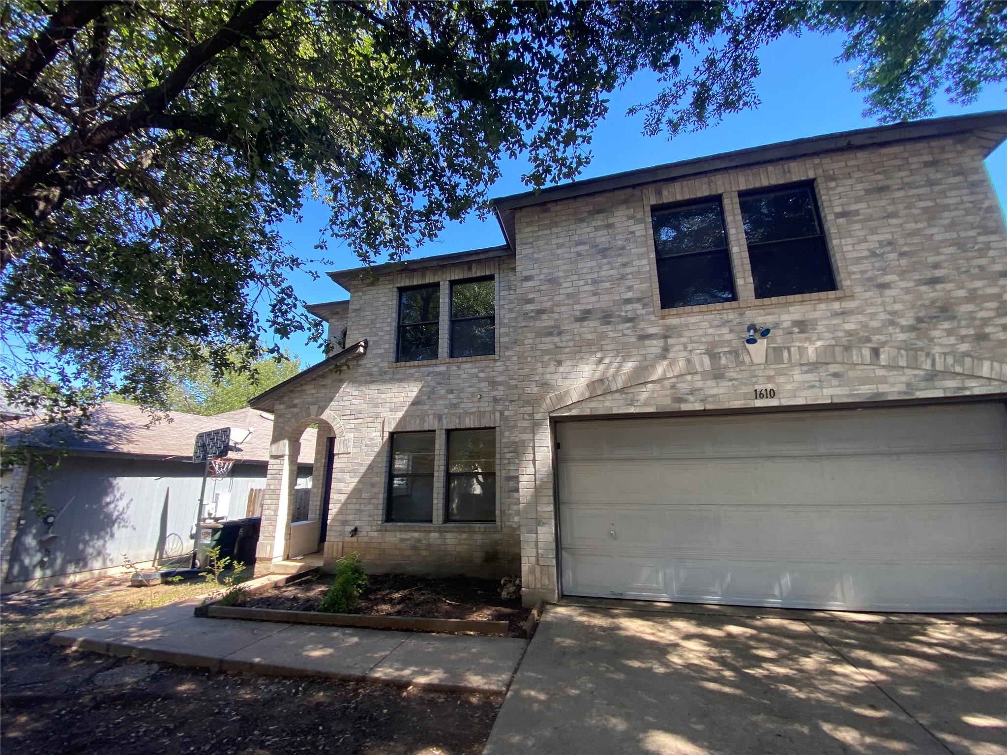 Mature trees shade a classic two-story brick faca