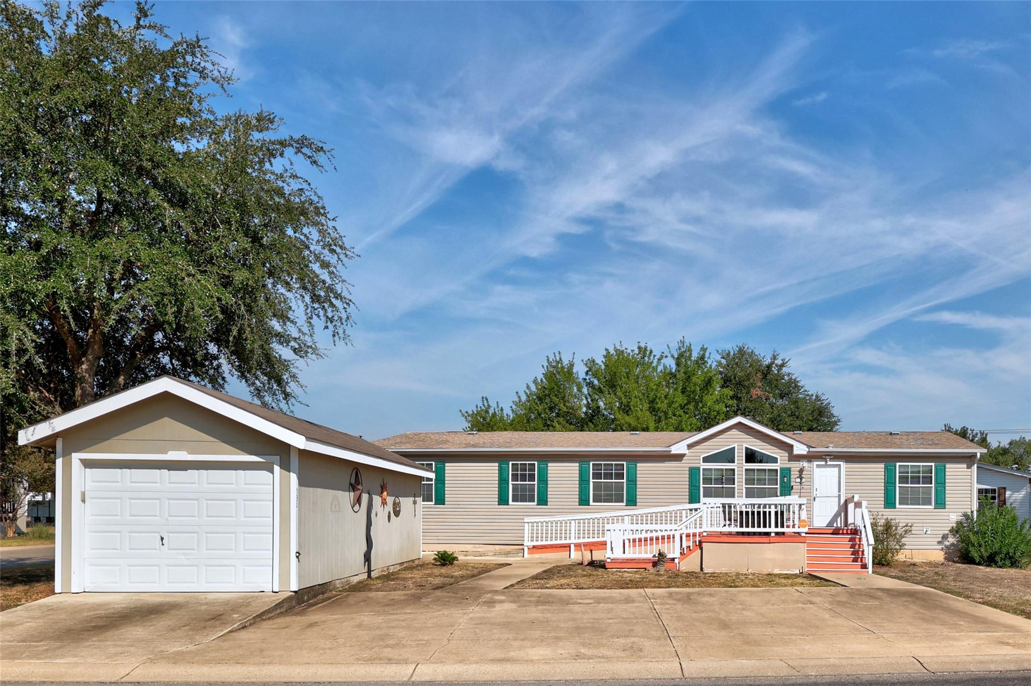 A spacious driveway and detached garage stand bef