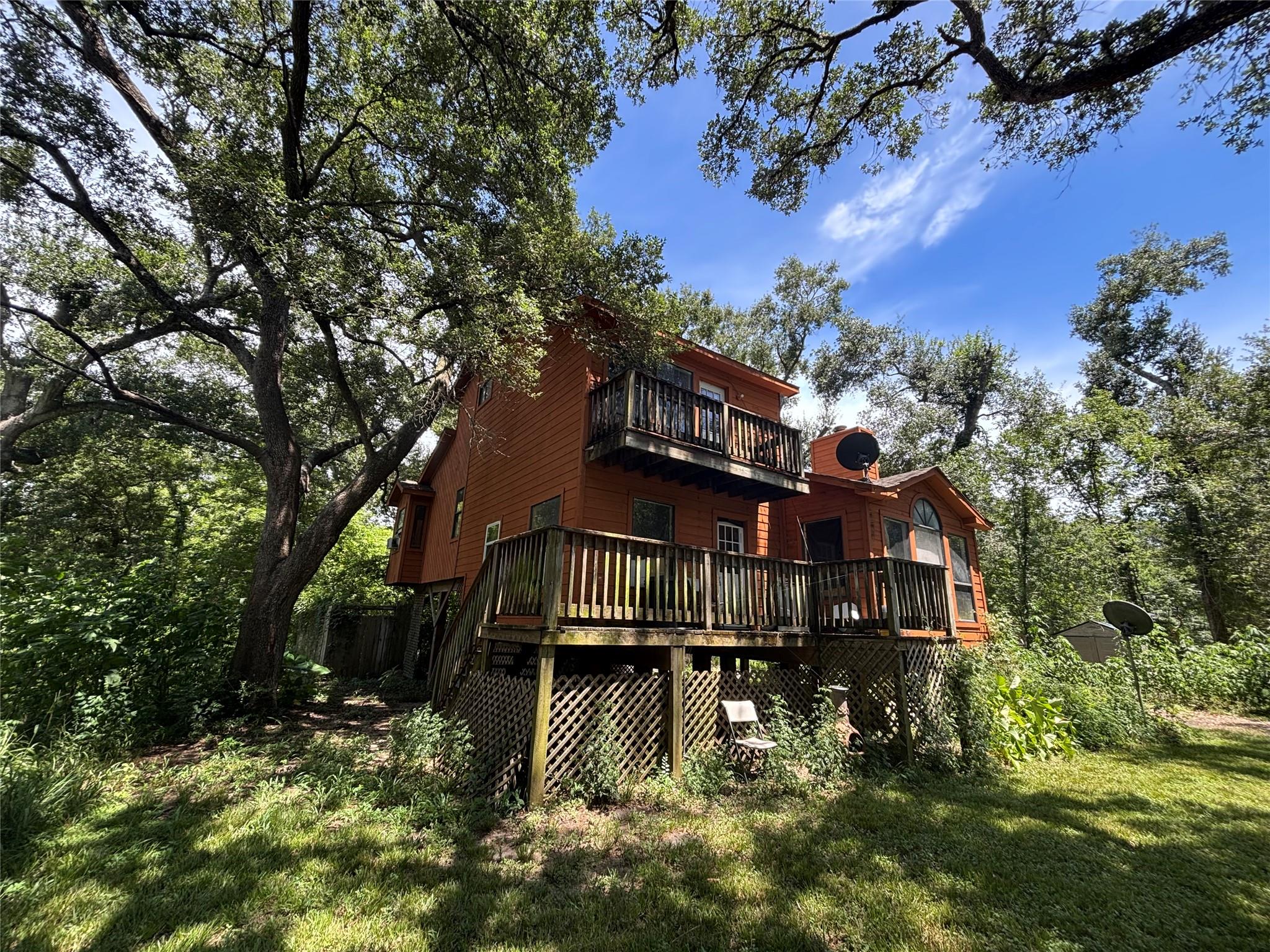 Mature trees shade a multi-level wooden deck atta