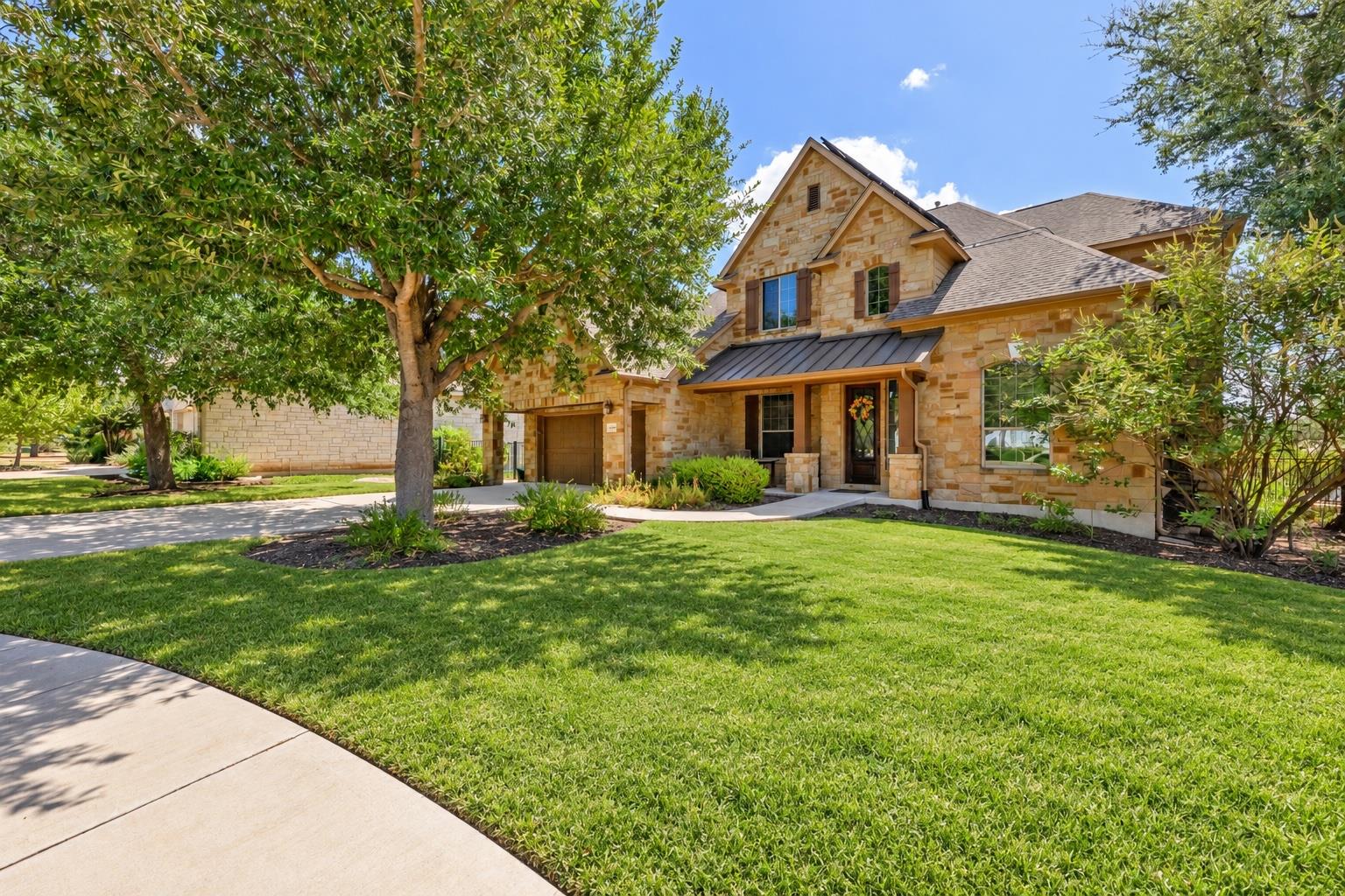 Mature trees shade a manicured lawn leading up to