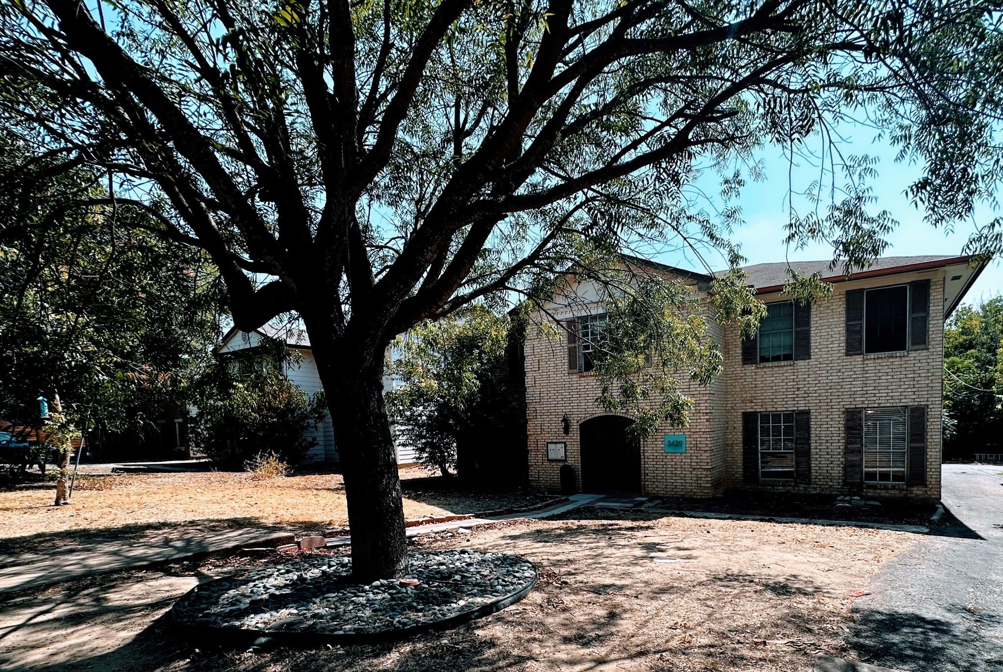 Mature trees shade the classic brick exterior of 