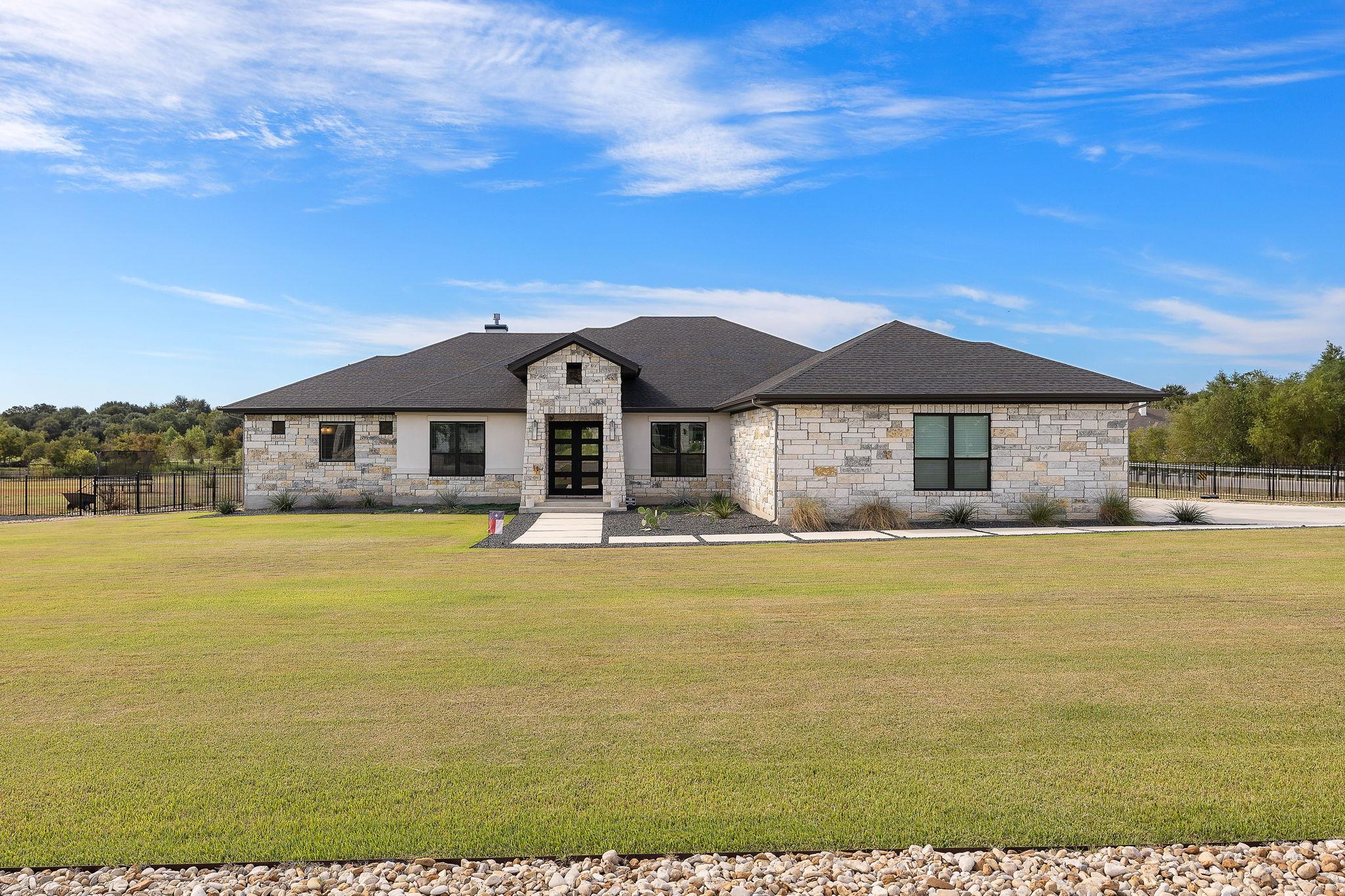 A spacious green lawn accents the stone facade of
