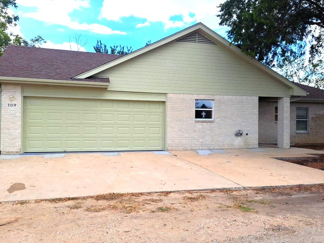 Brick accents and a spacious concrete driveway le