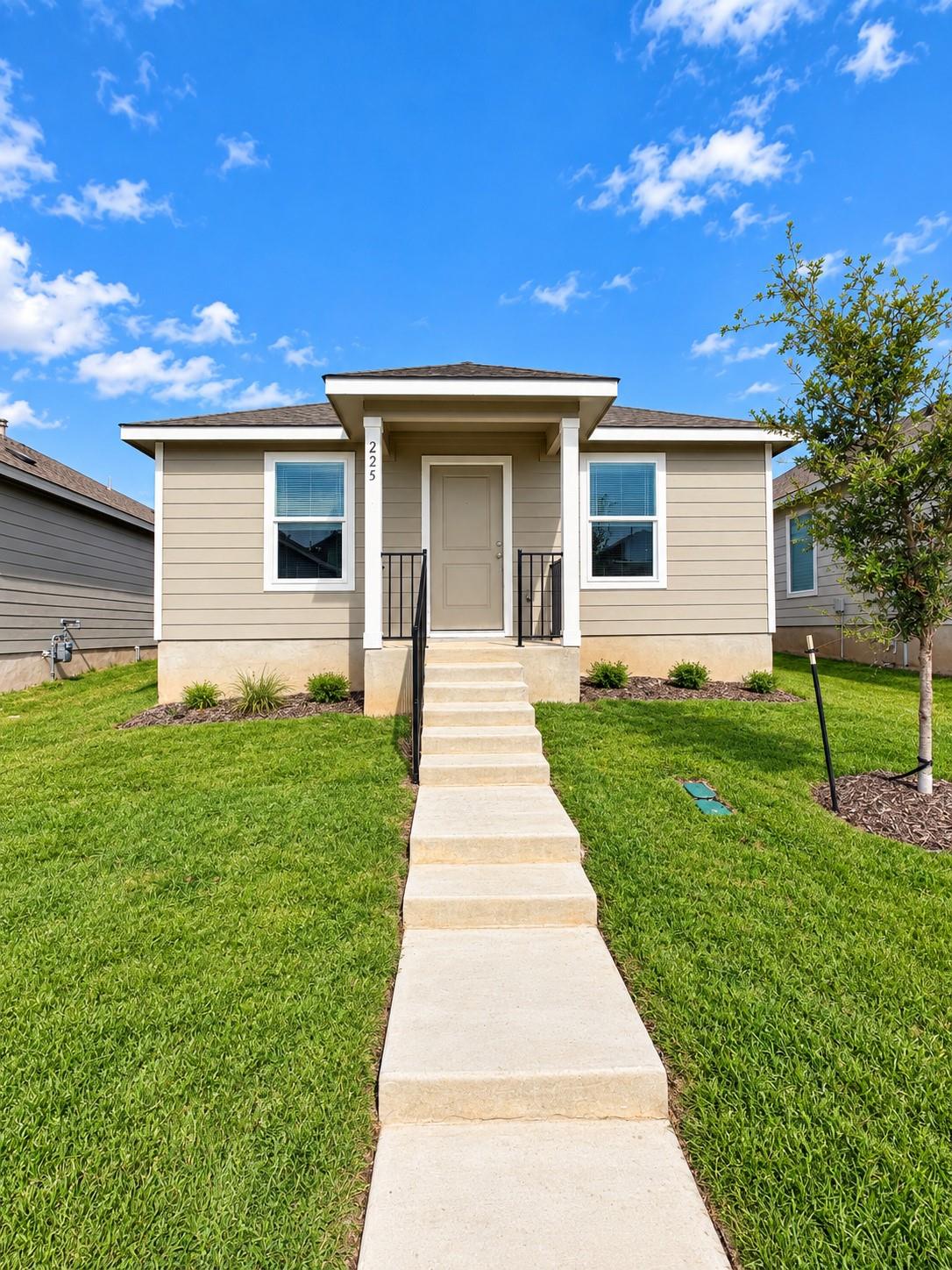 A neat concrete walkway leads up to the inviting 