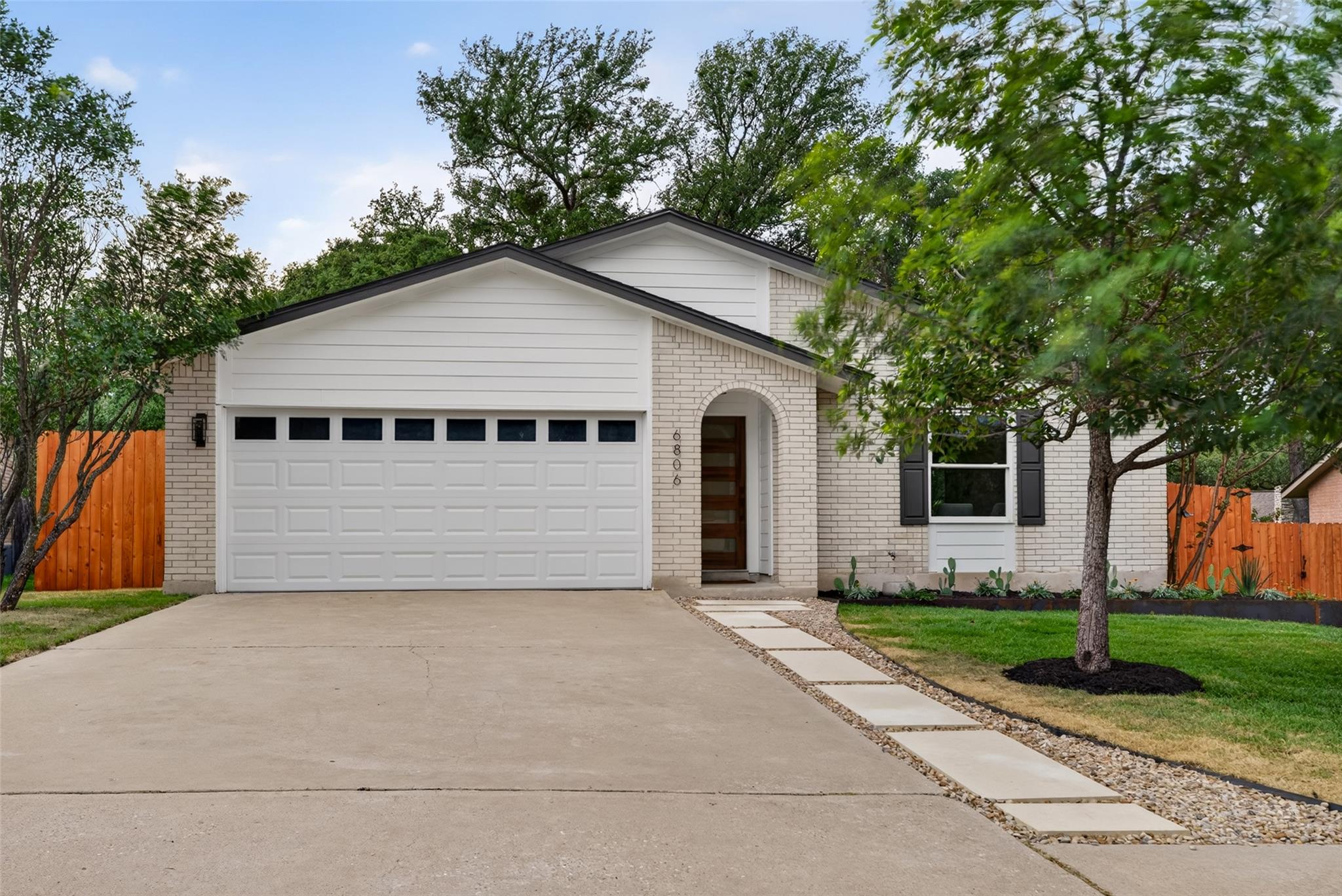 White brick exterior with a wood-finish entry doo