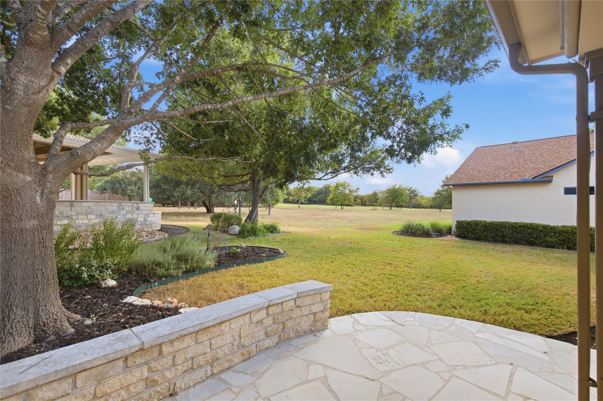 Mature trees shade a flagstone patio looking out 