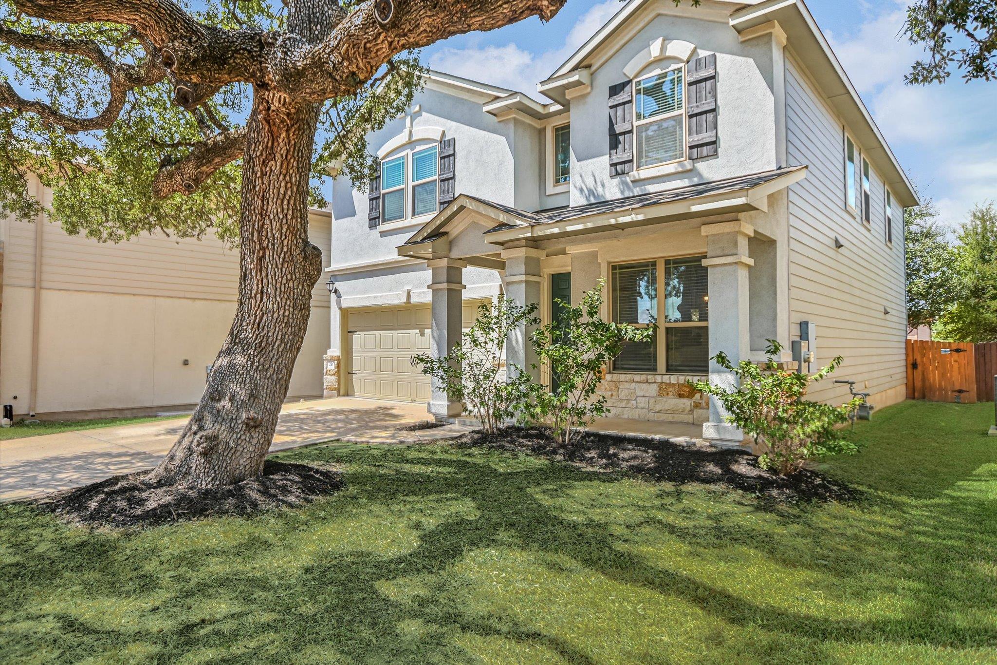 Mature oak trees shade a manicured front lawn in 