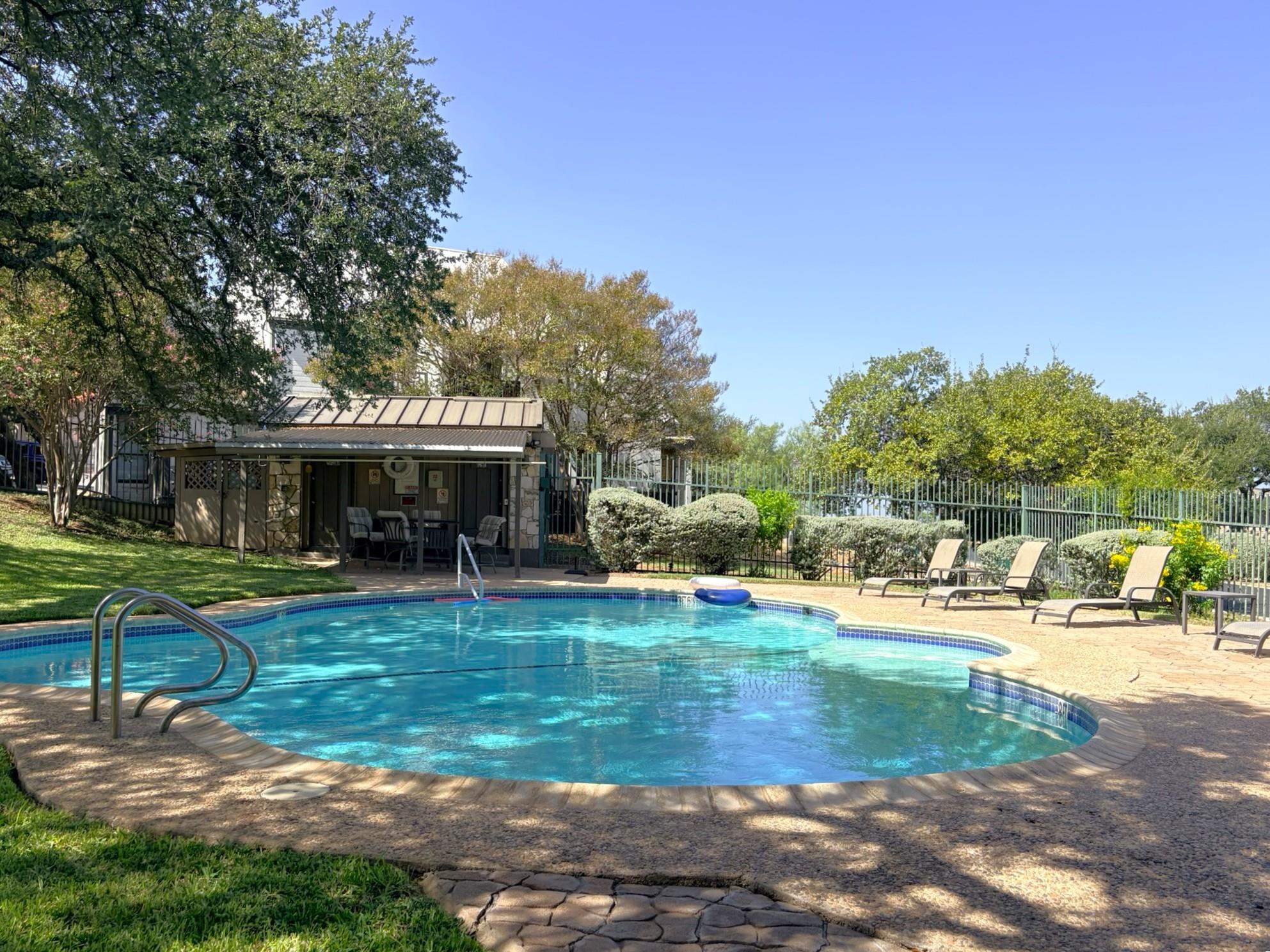 Mature trees frame a sparkling swimming pool bord