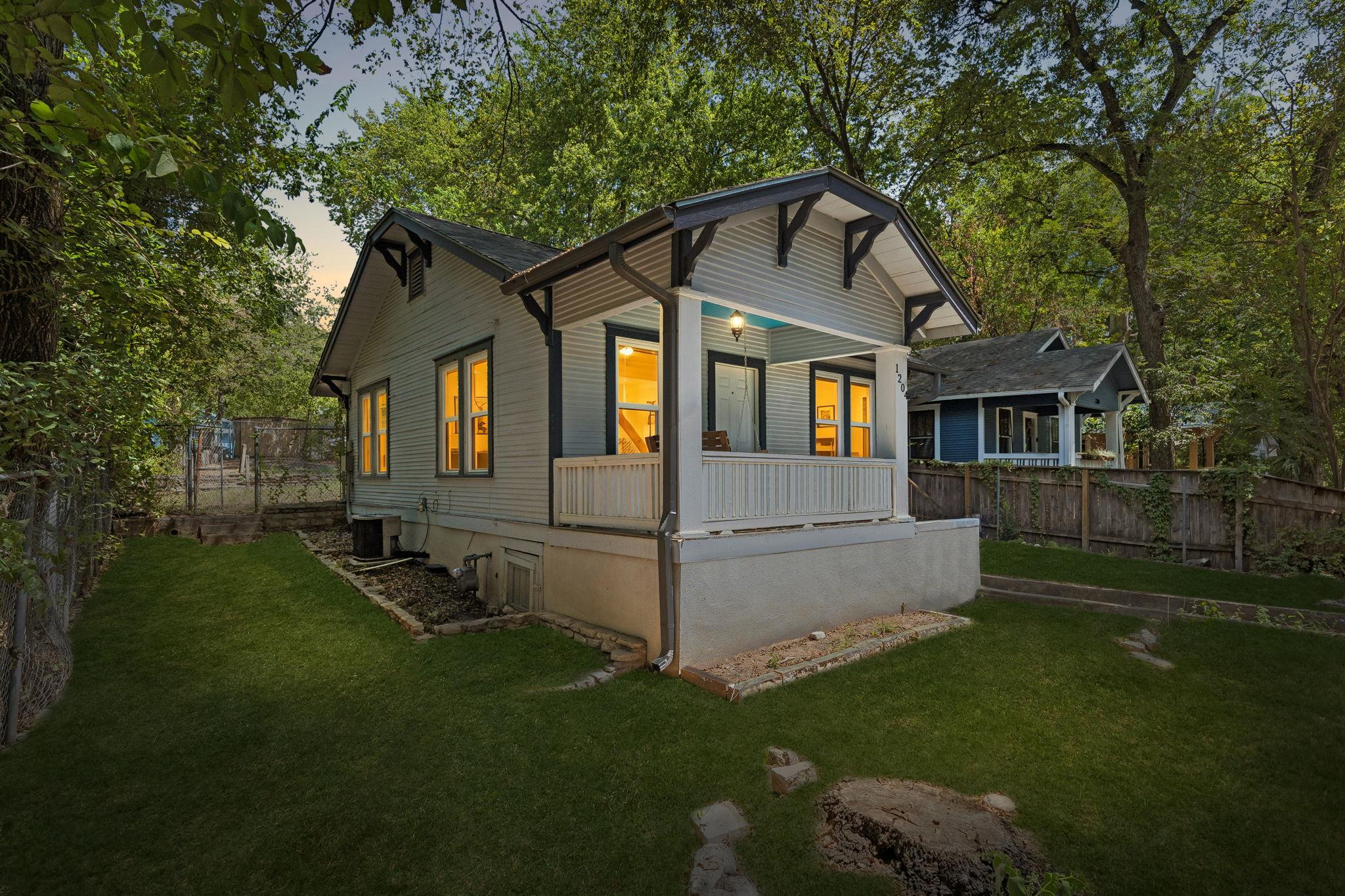 Mature trees frame a charming cottage featuring a