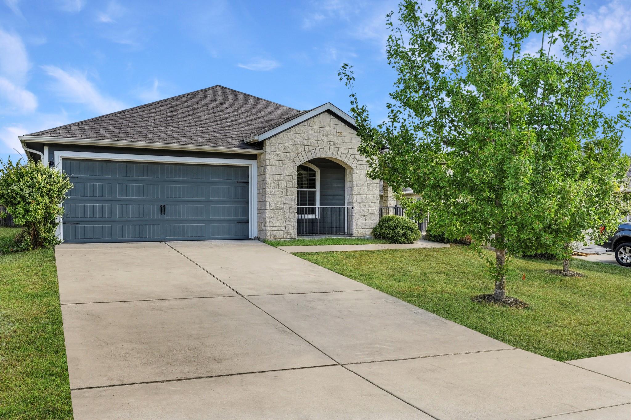 A wide concrete driveway leads past a neat lawn t