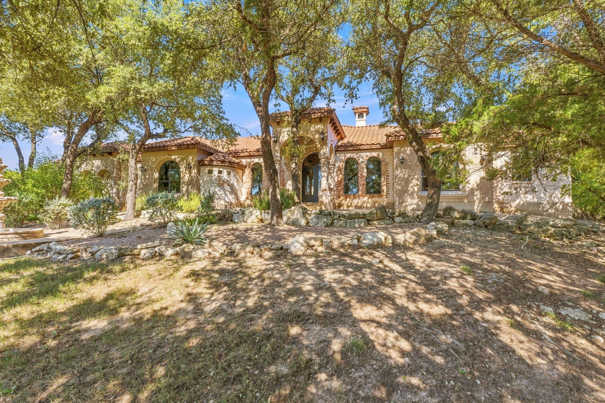 Mature trees frame a Mediterranean-style facade f