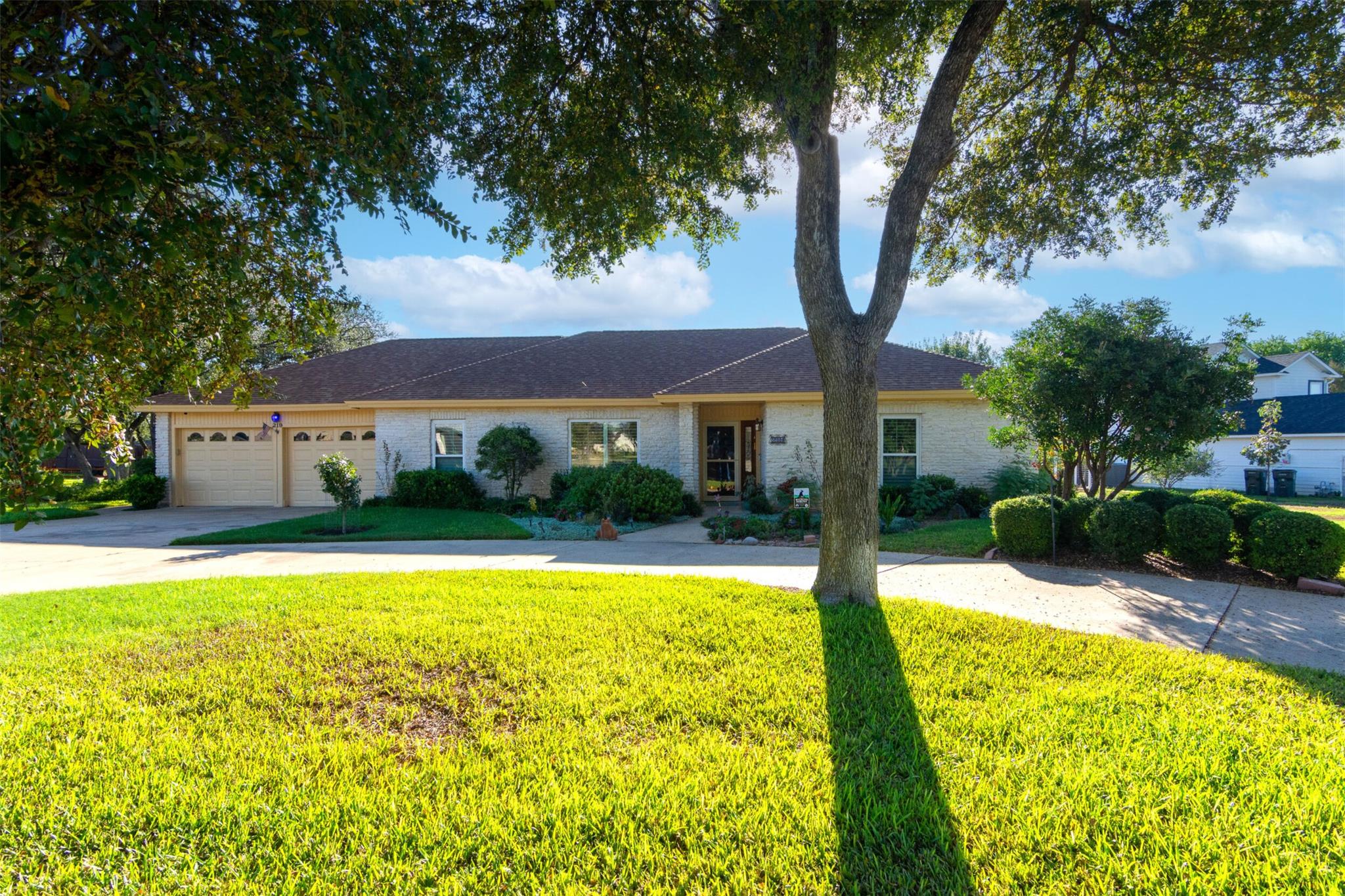 Mature shade trees and a manicured lawn frame thi