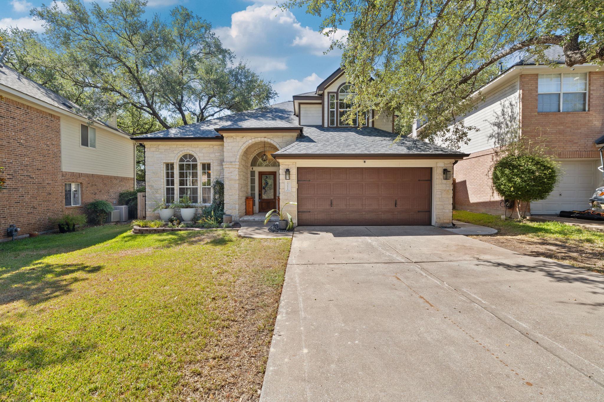 An arched stone entryway and wide concrete drivew