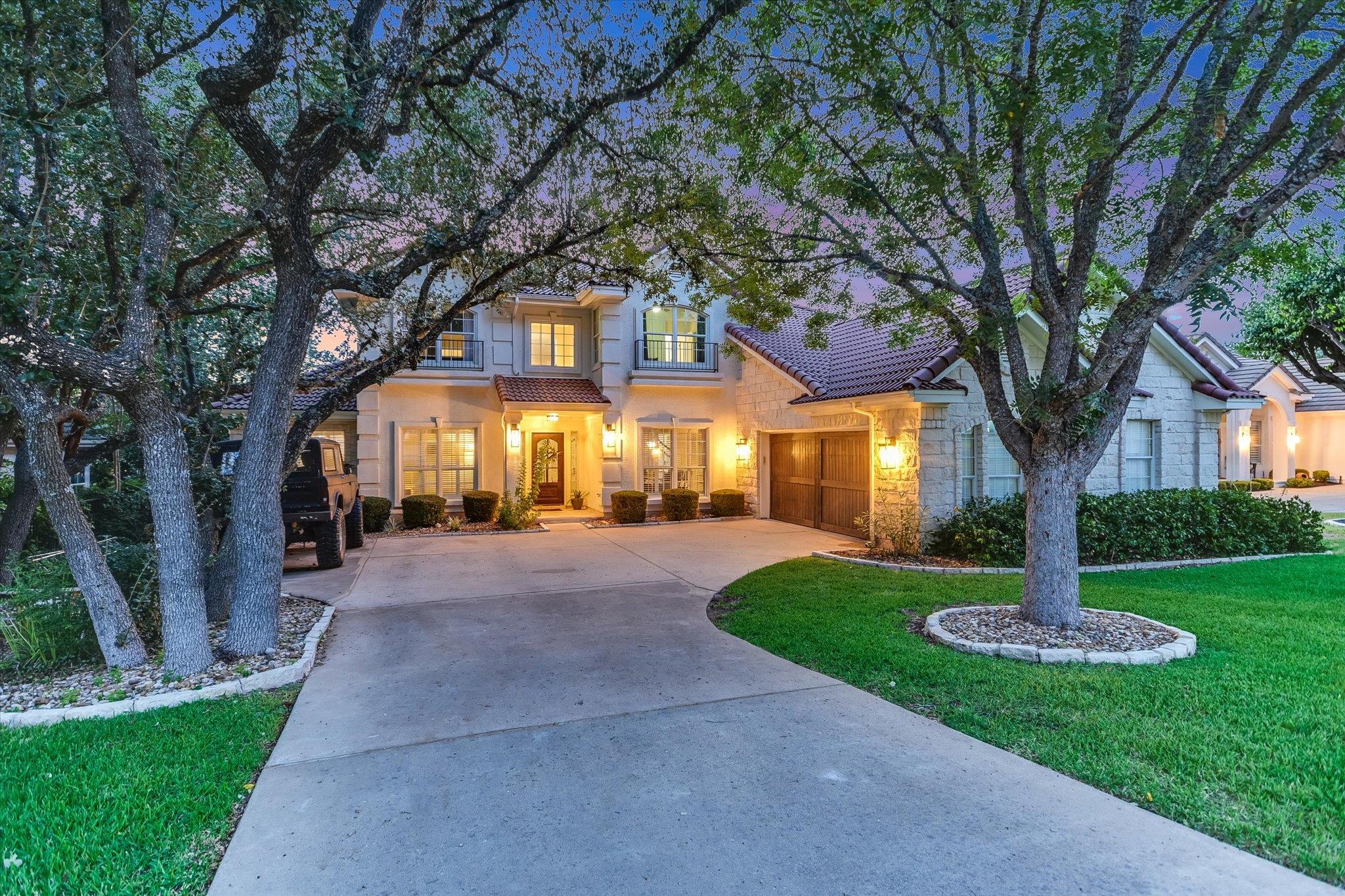 Mature trees frame the stone and stucco facade of