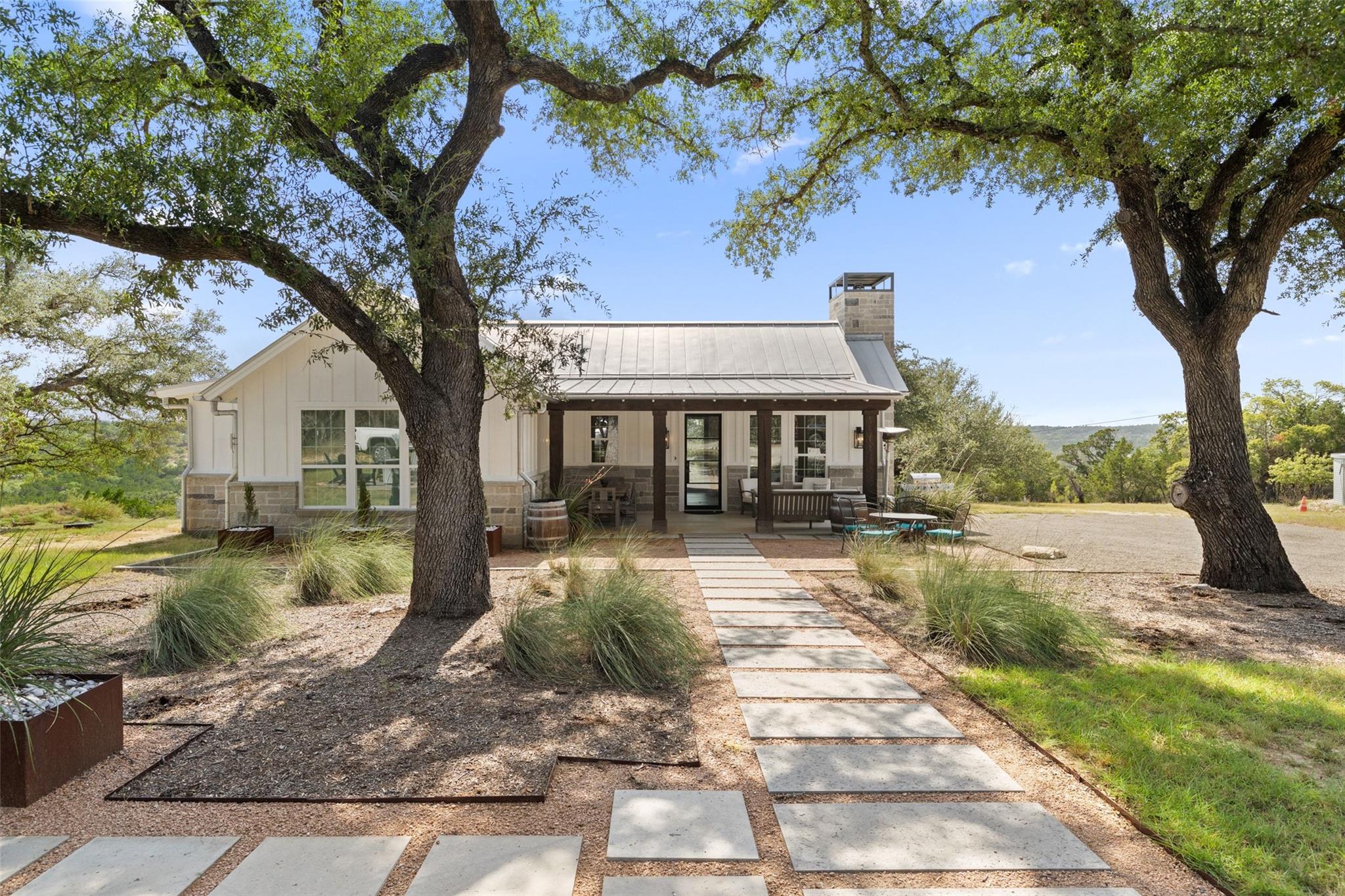 Mature oak trees frame a modern farmhouse featuri