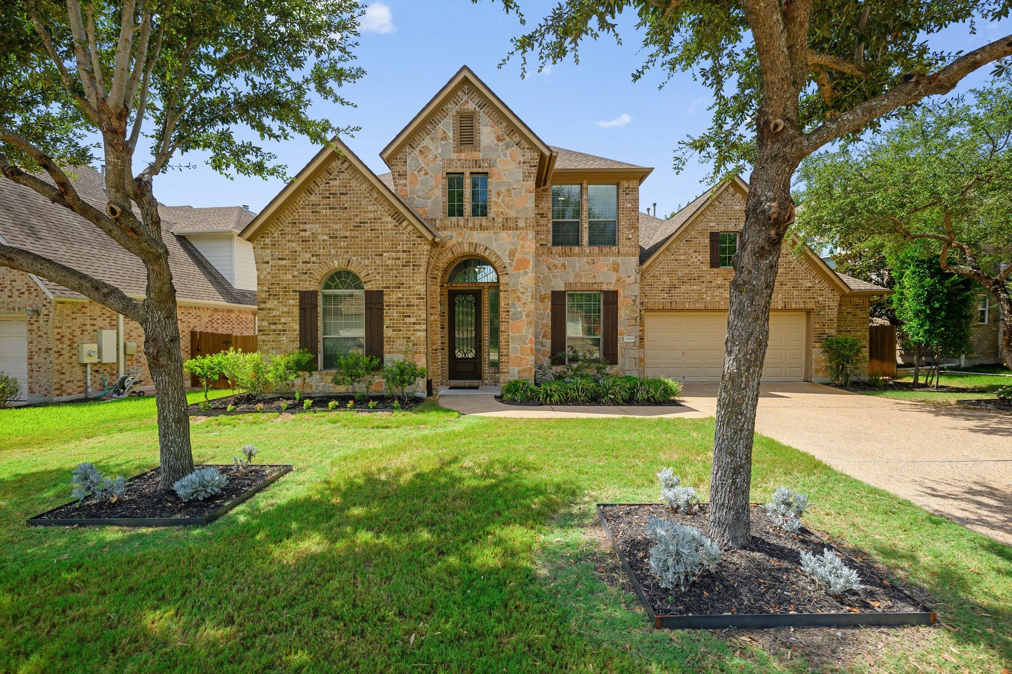 Mature trees frame the stone and brick exterior o