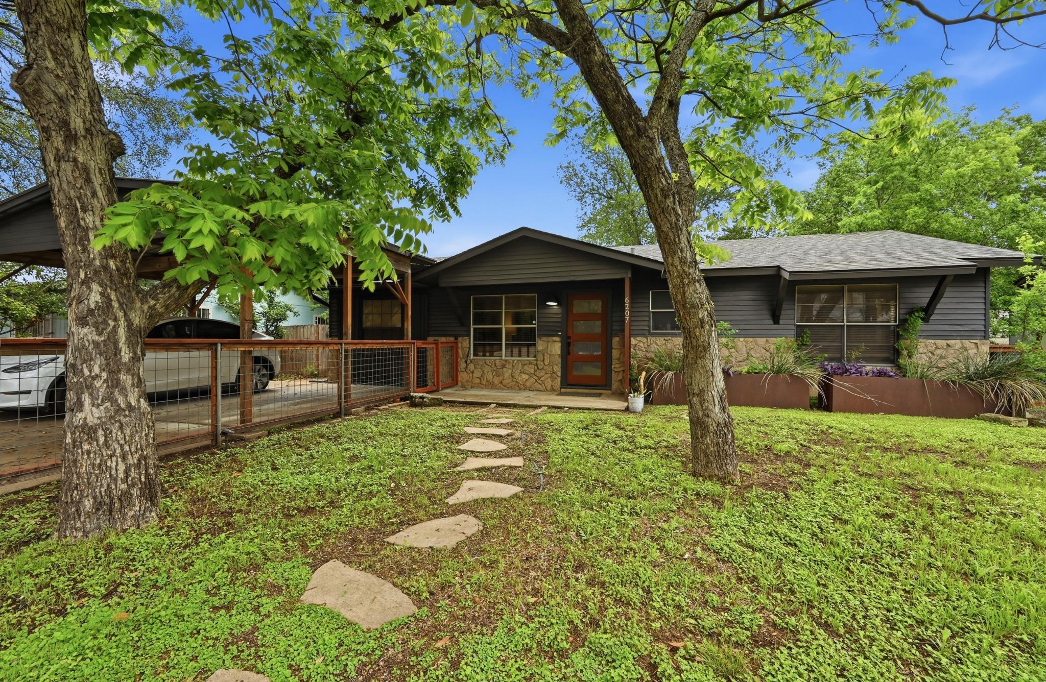 Mature trees shade a welcoming flagstone path lea