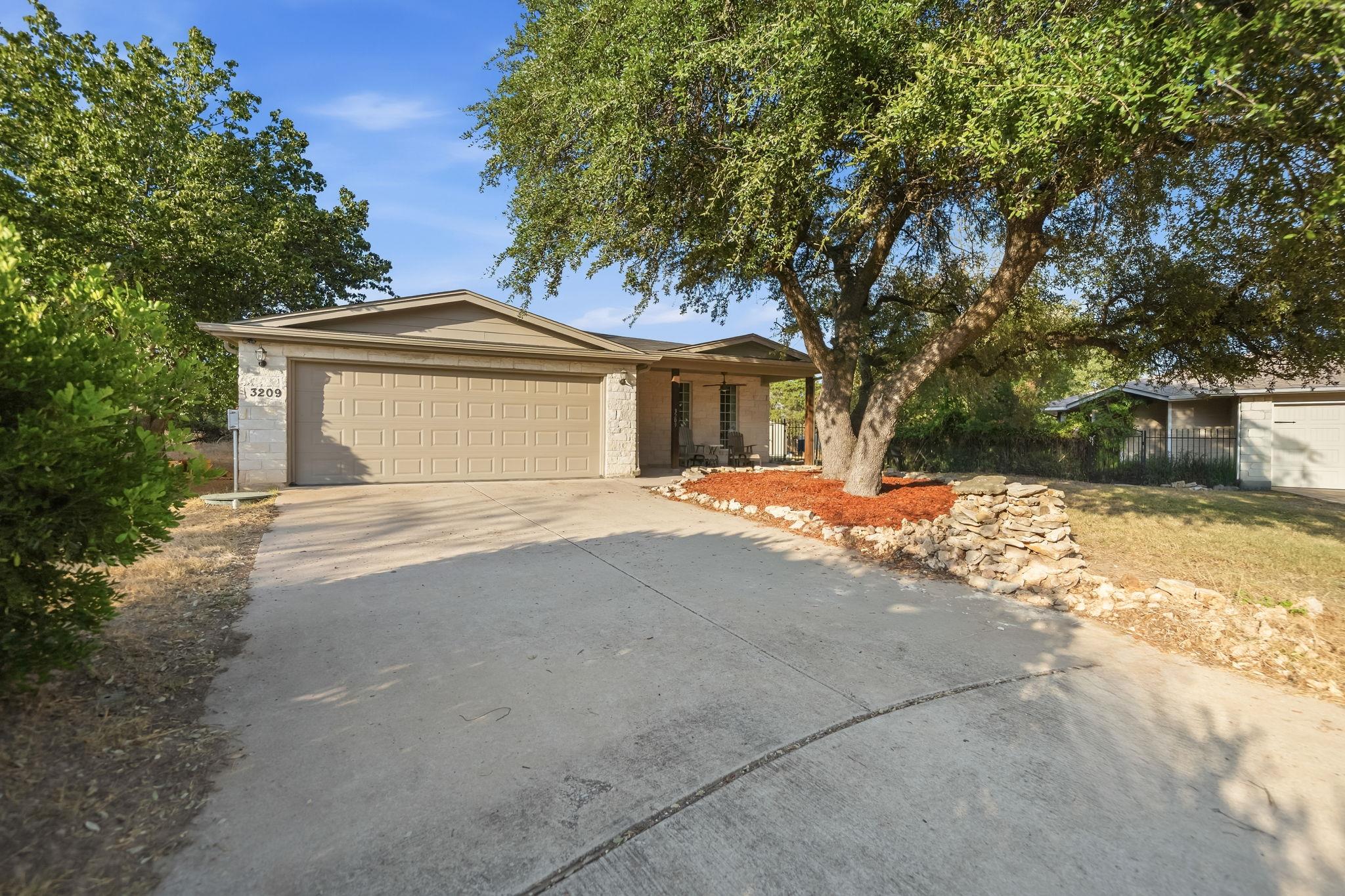 Mature shade trees and a wide concrete driveway f