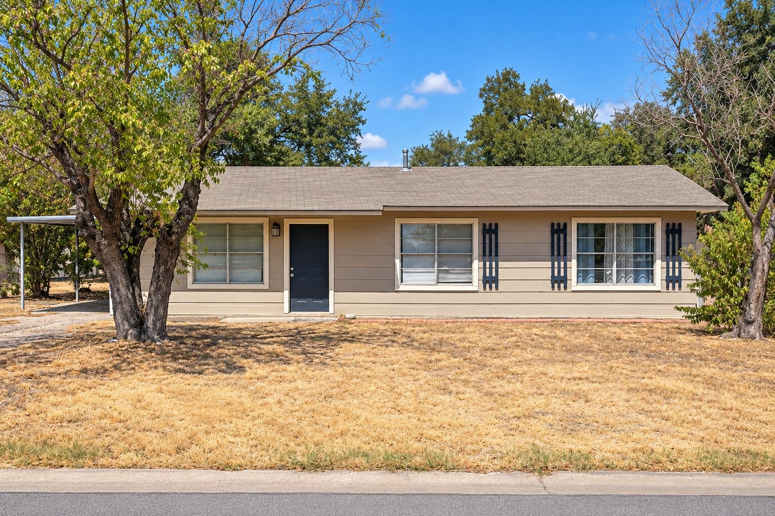 Mature trees frame this classic single-story home