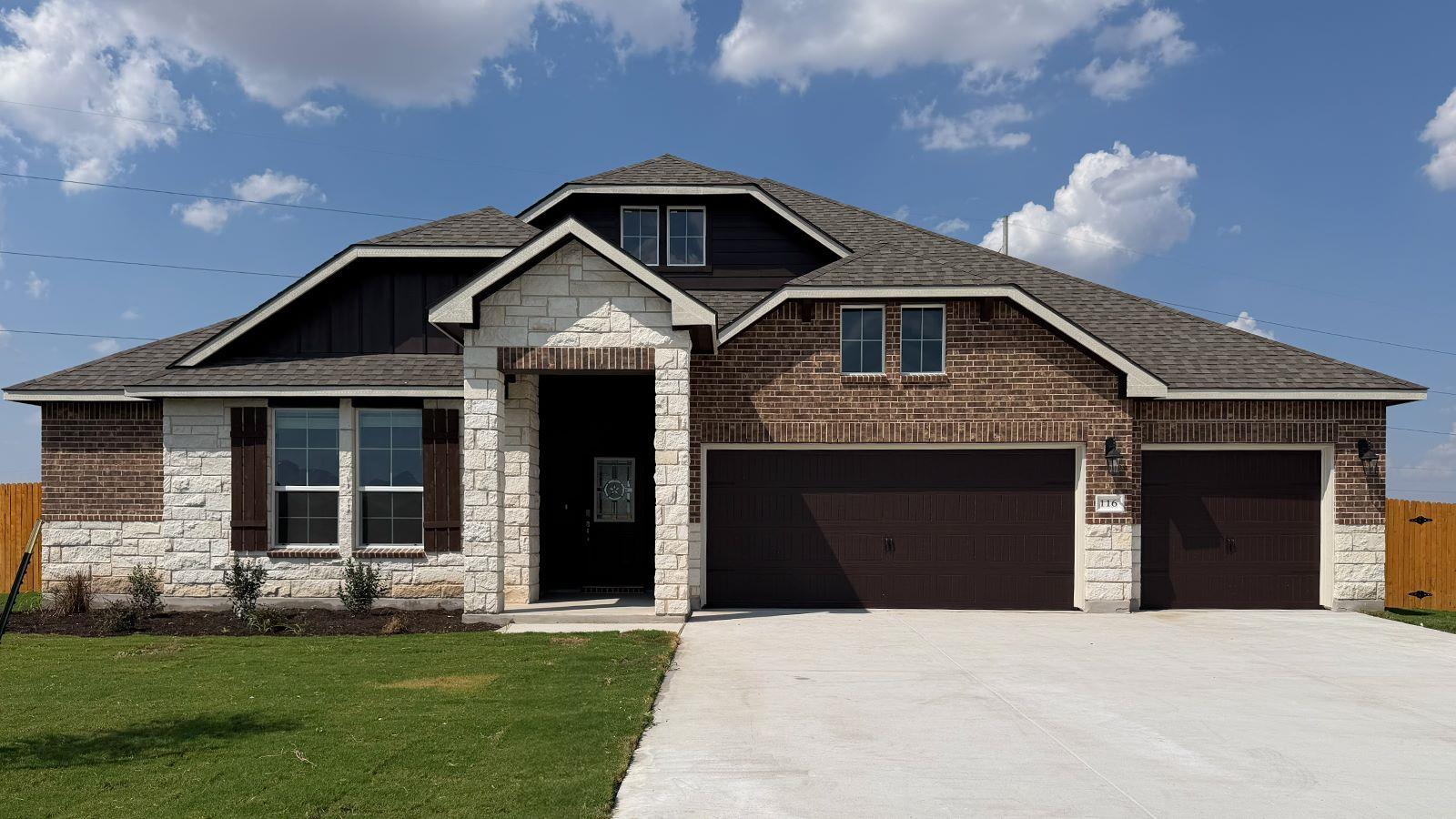 A spacious driveway leads to this stone and brick