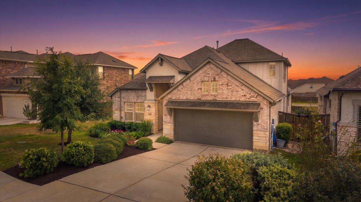 Manicured landscaping accents the stone and brick