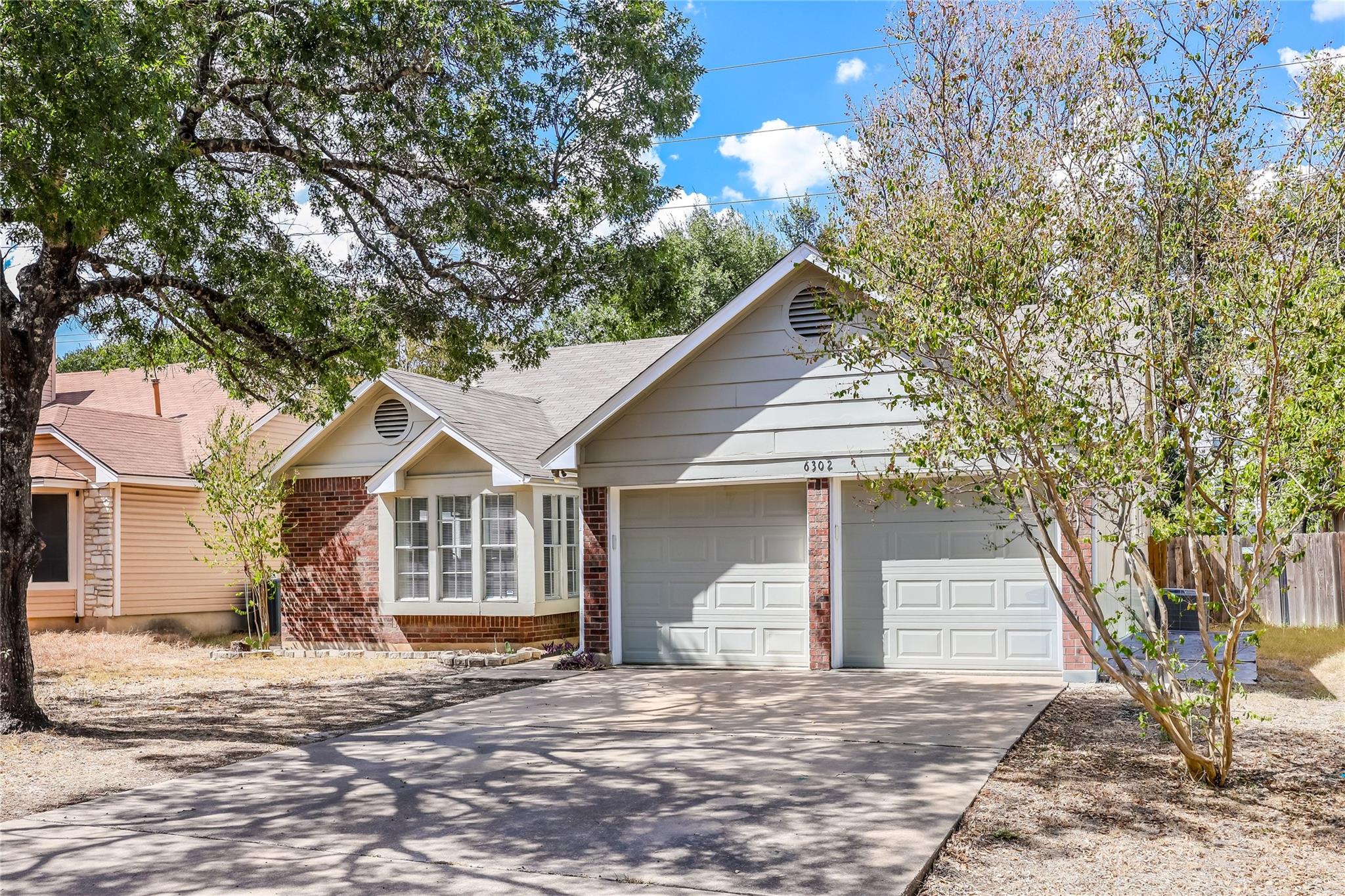 Mature trees shade the driveway and exterior of t
