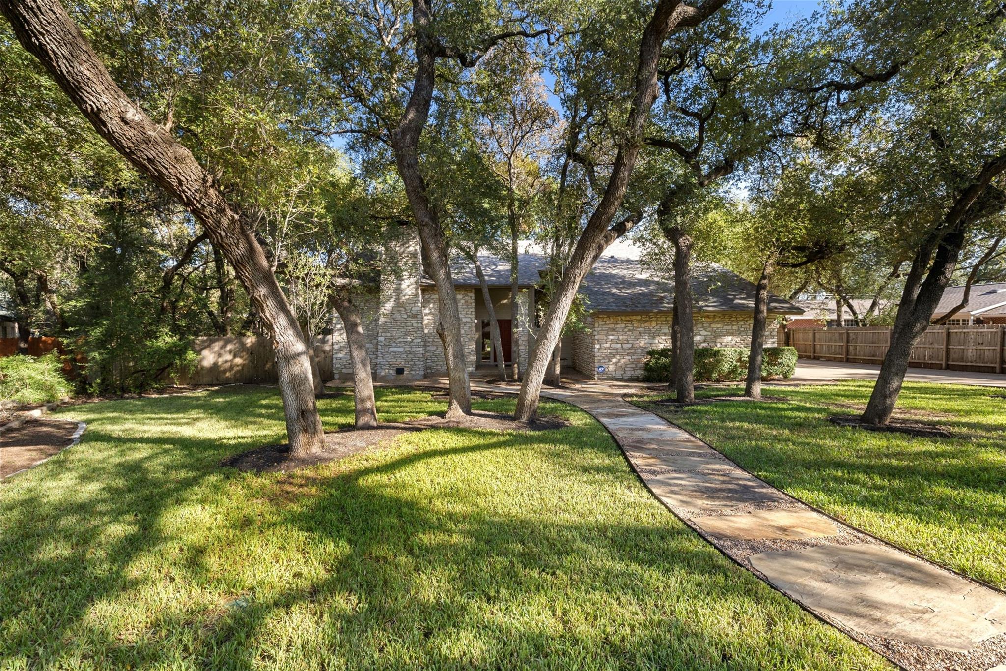 Mature shade trees and a stone pathway lead to th