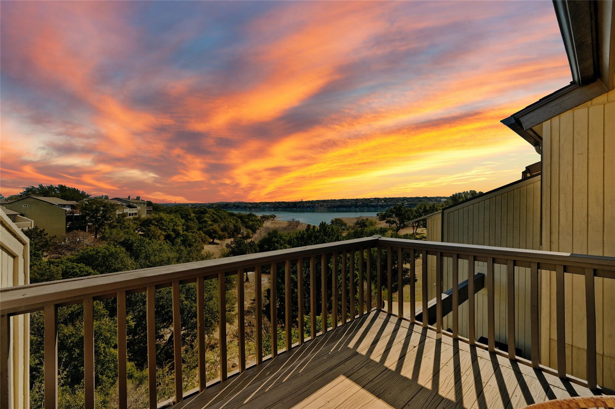 A spacious wooden balcony overlooks serene lake w