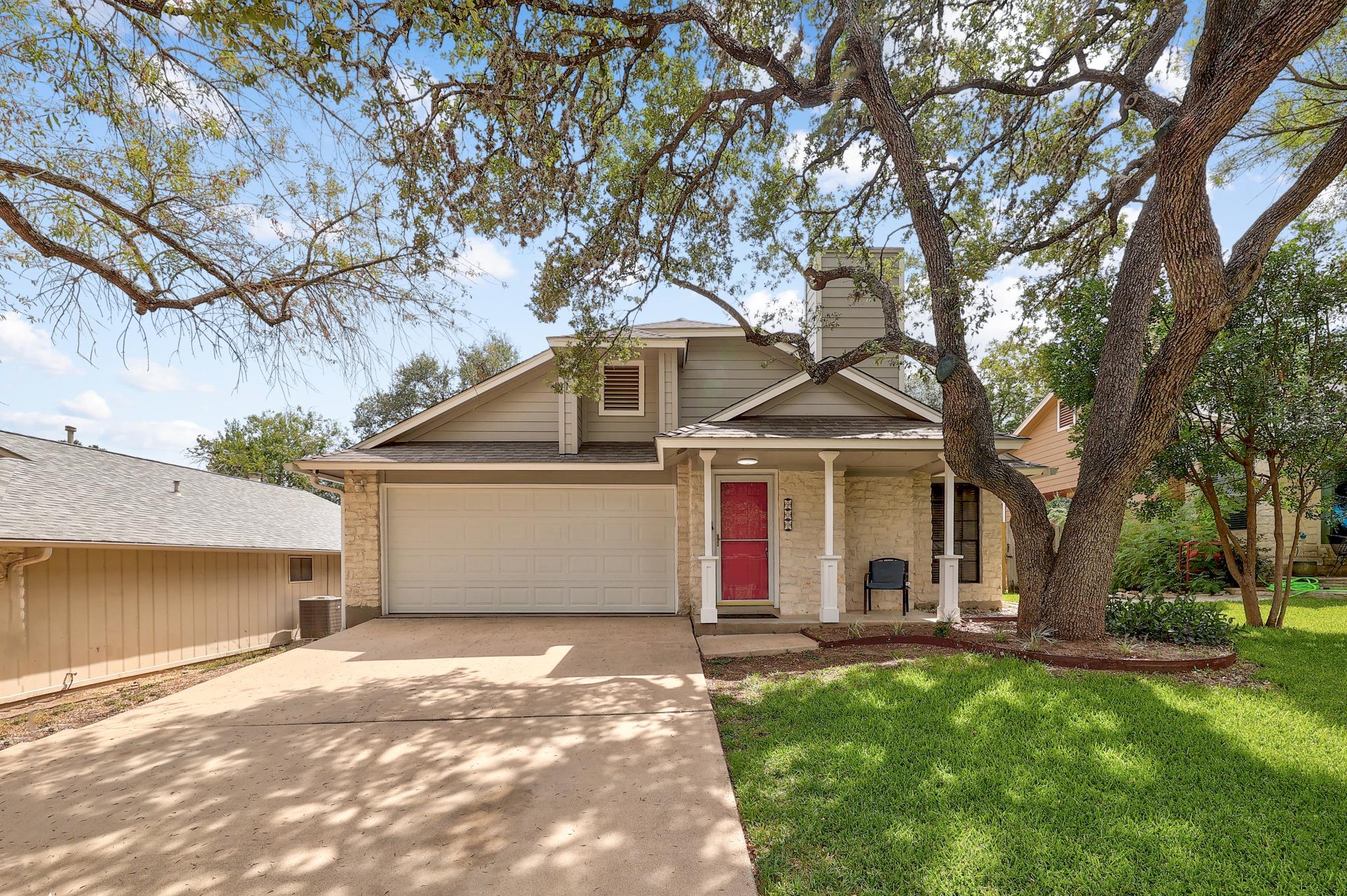 Mature trees shade a welcoming front porch, concr
