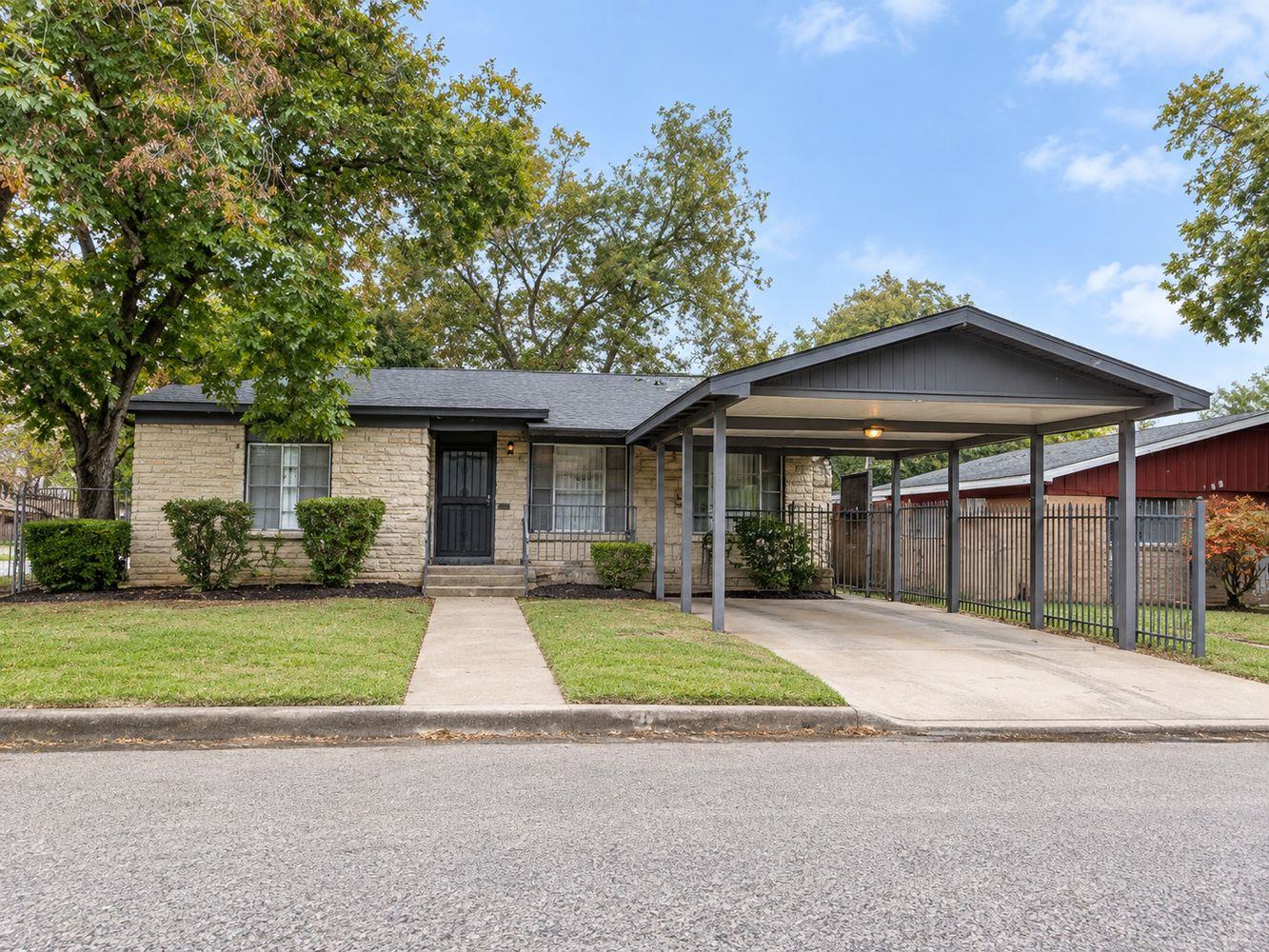 Mature trees frame a classic stone exterior featu