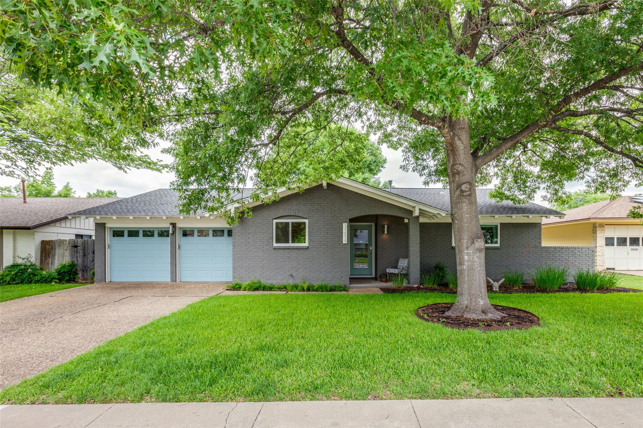Mature shade trees frame a classic single-story b