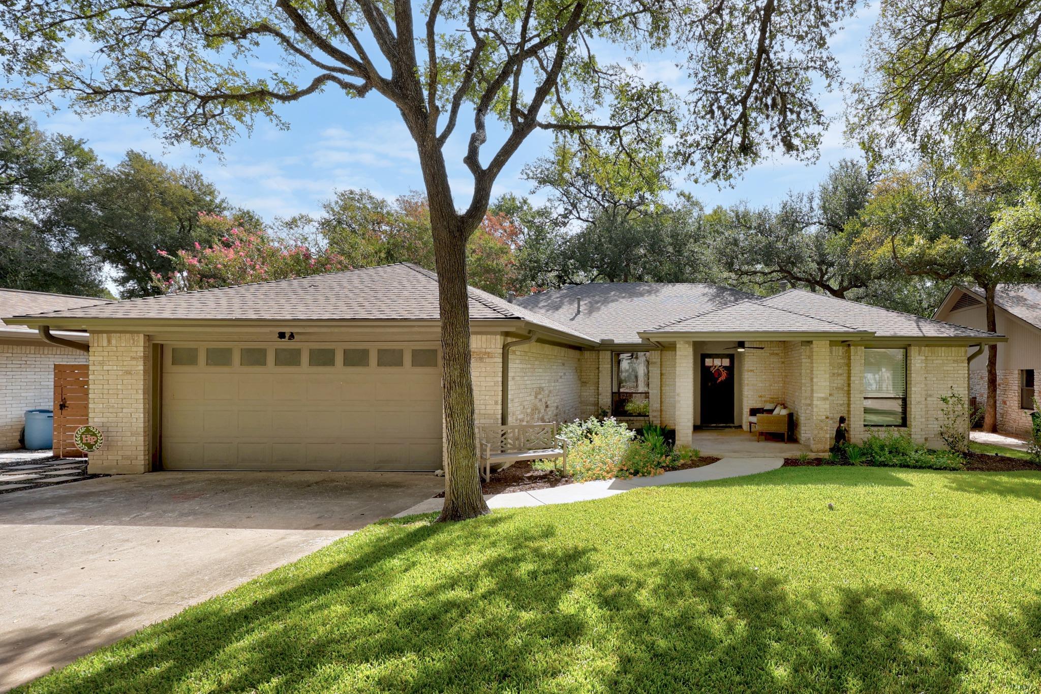 Mature trees shade a classic single-story brick f