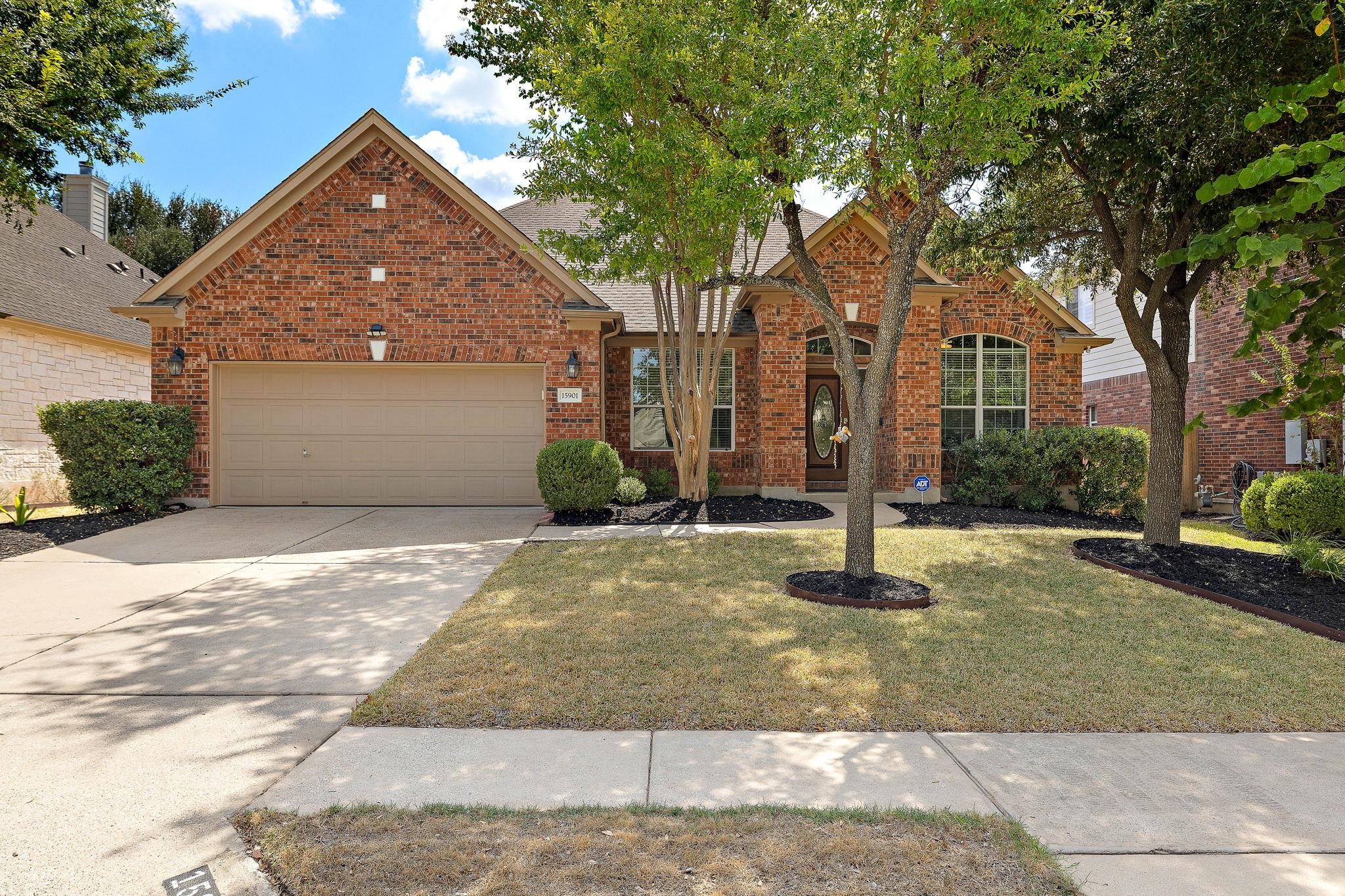 Mature trees shade the manicured front lawn leadi