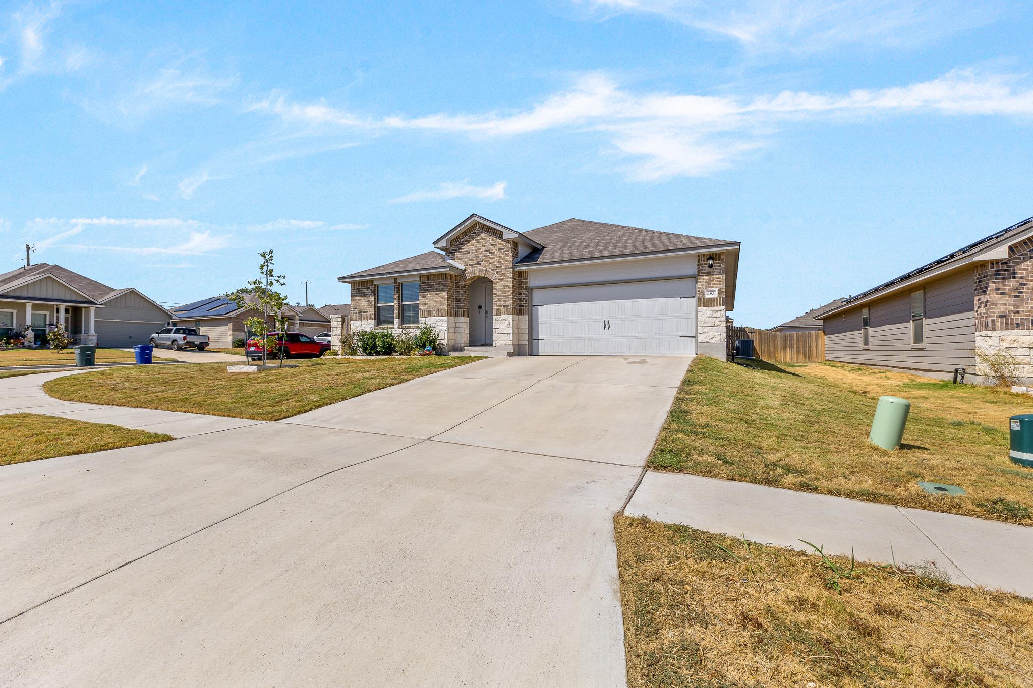 A spacious concrete driveway leads to this modern