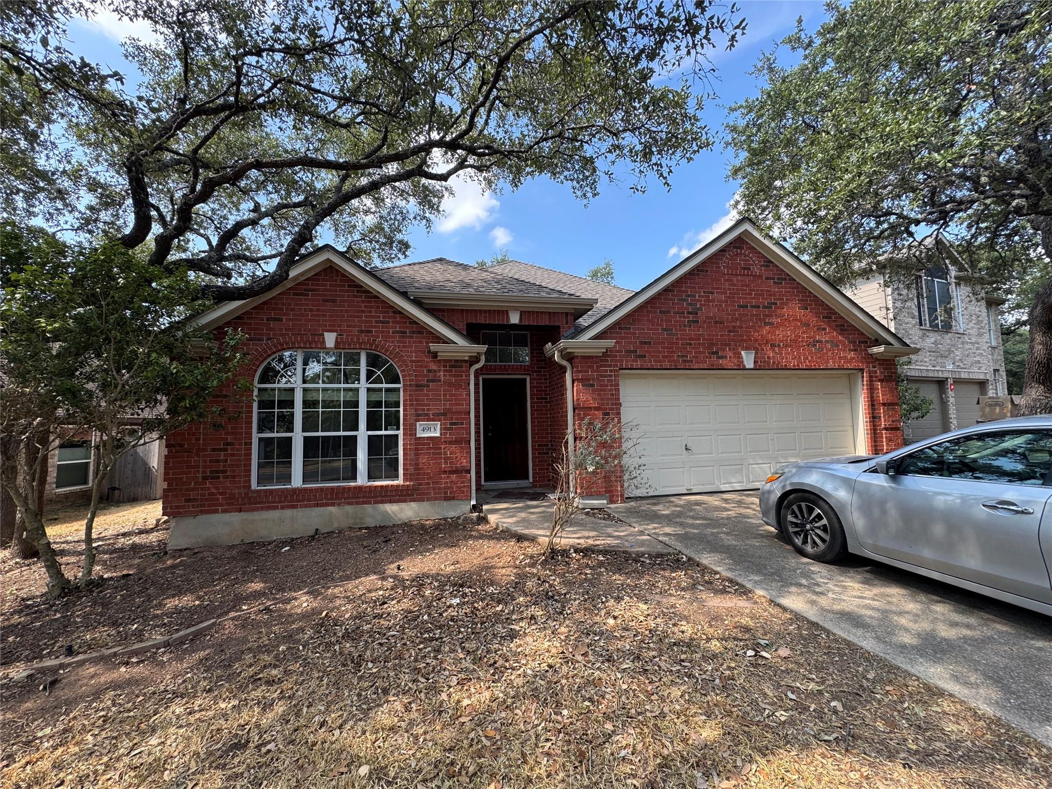 Mature trees frame a classic brick exterior featu