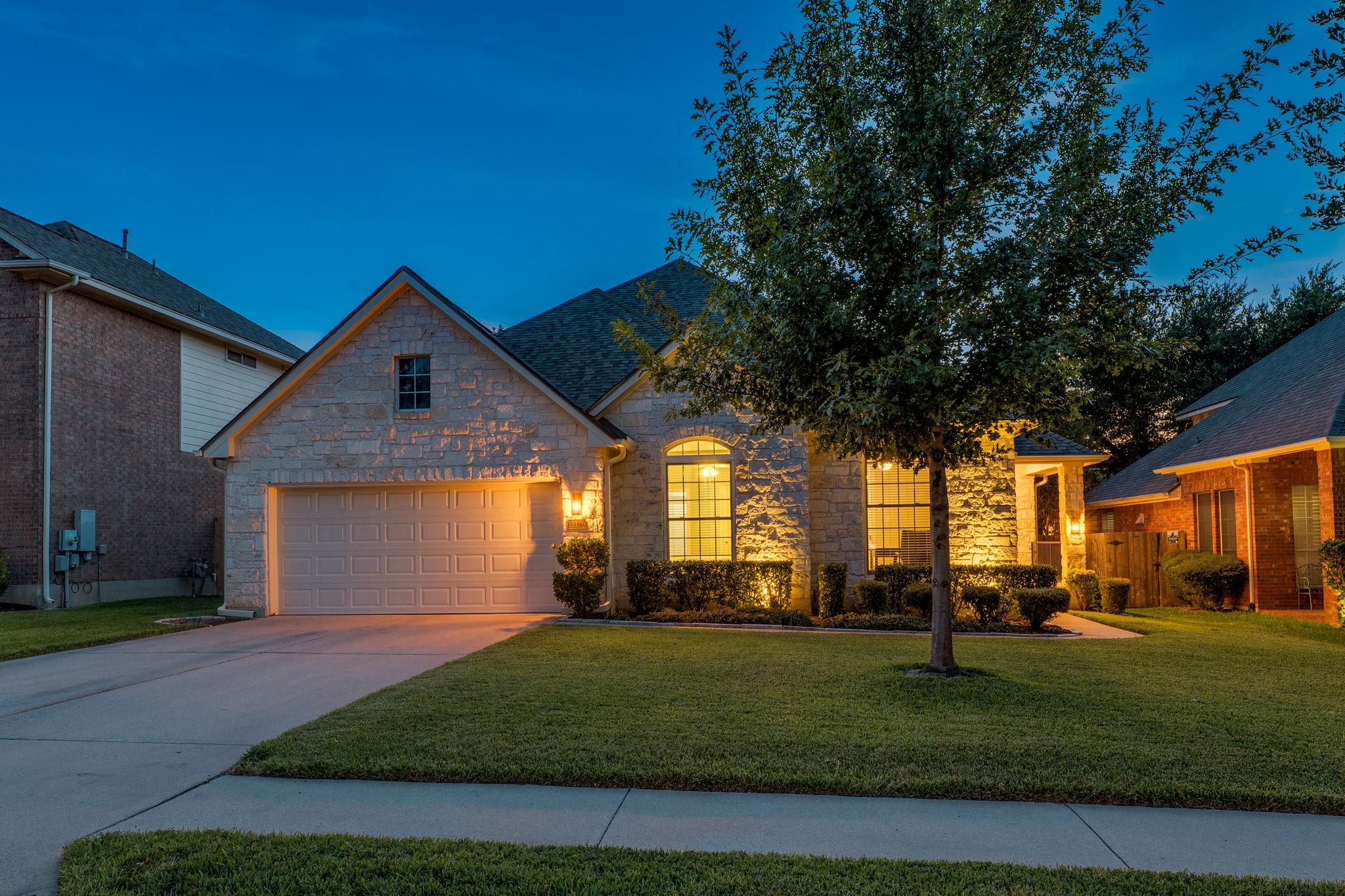 Textured stone siding and manicured green lawns f