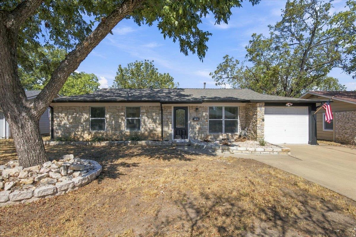 Mature trees shade a classic single-story stone f