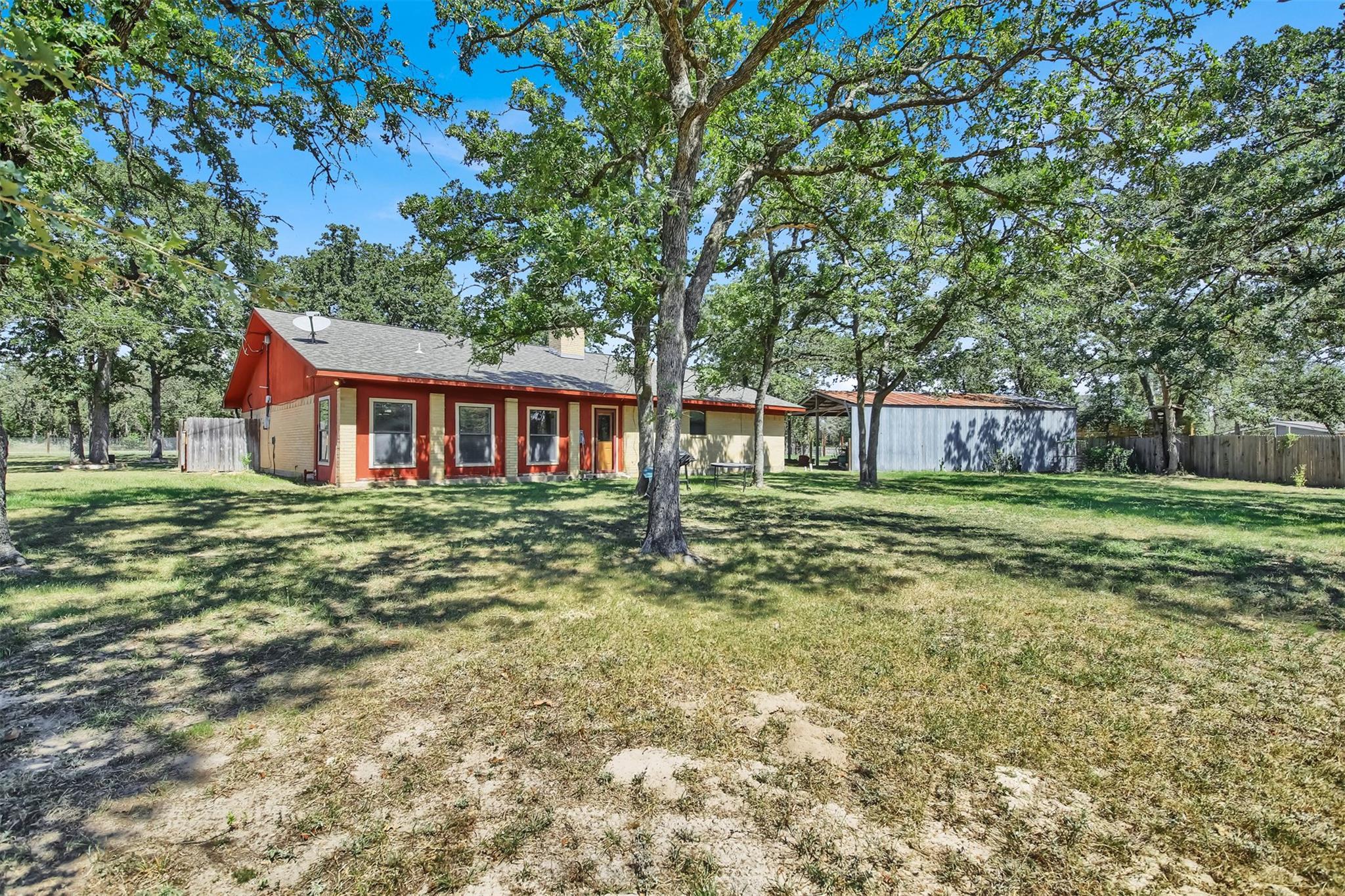 Mature oak trees shade a spacious backyard featur