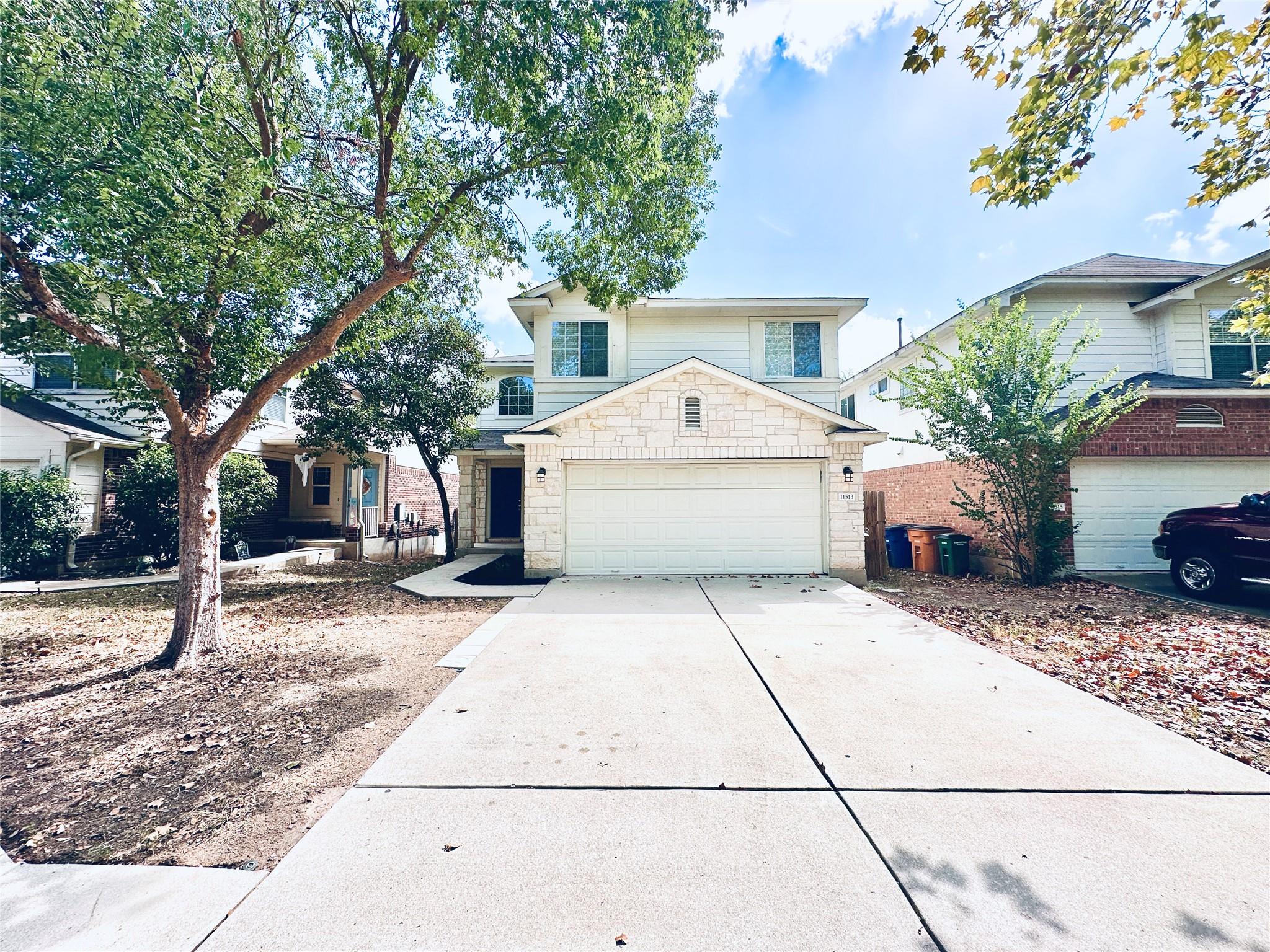 Mature trees shade the concrete driveway leading 