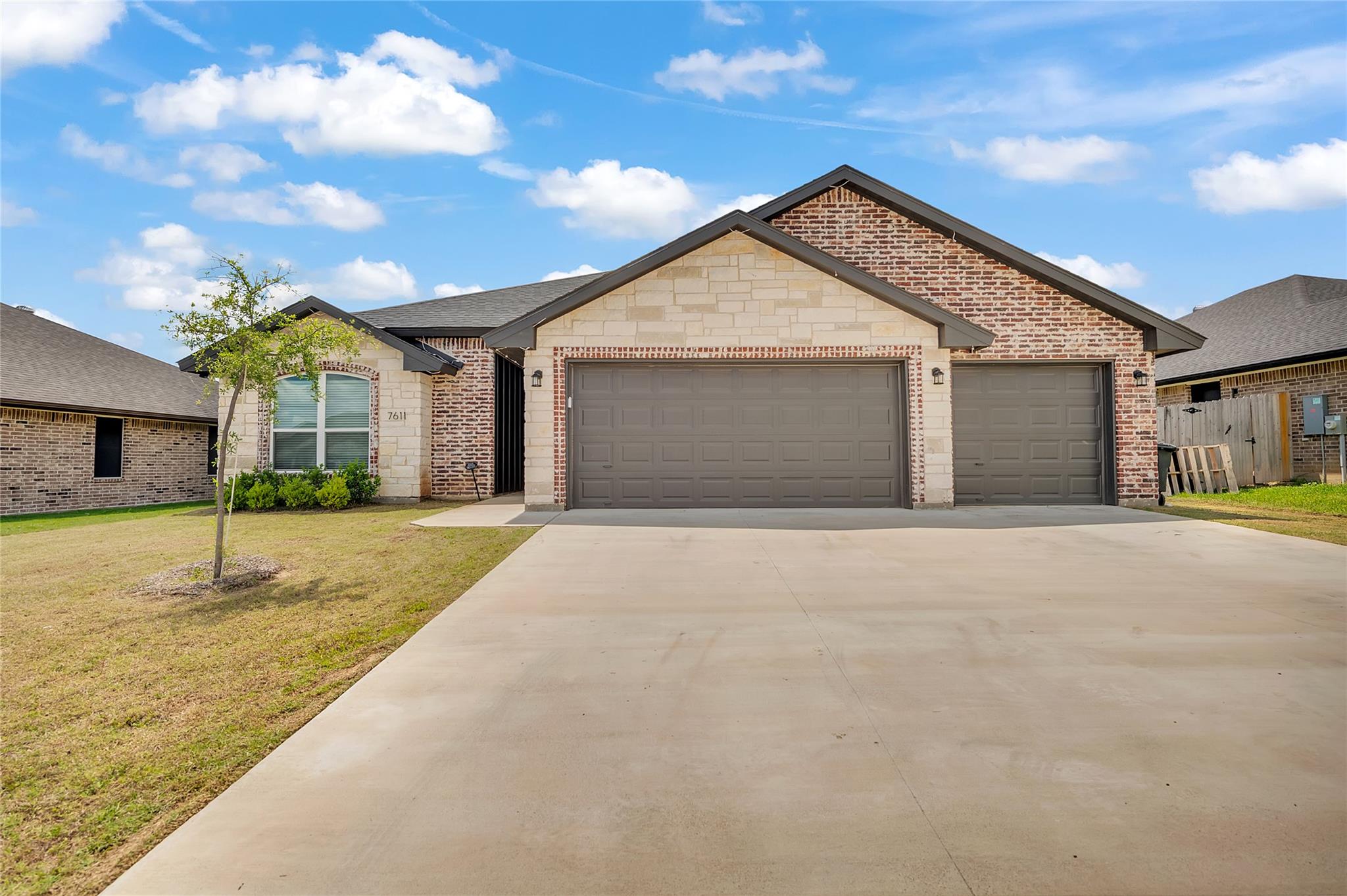 An expansive concrete driveway leads to a three-c