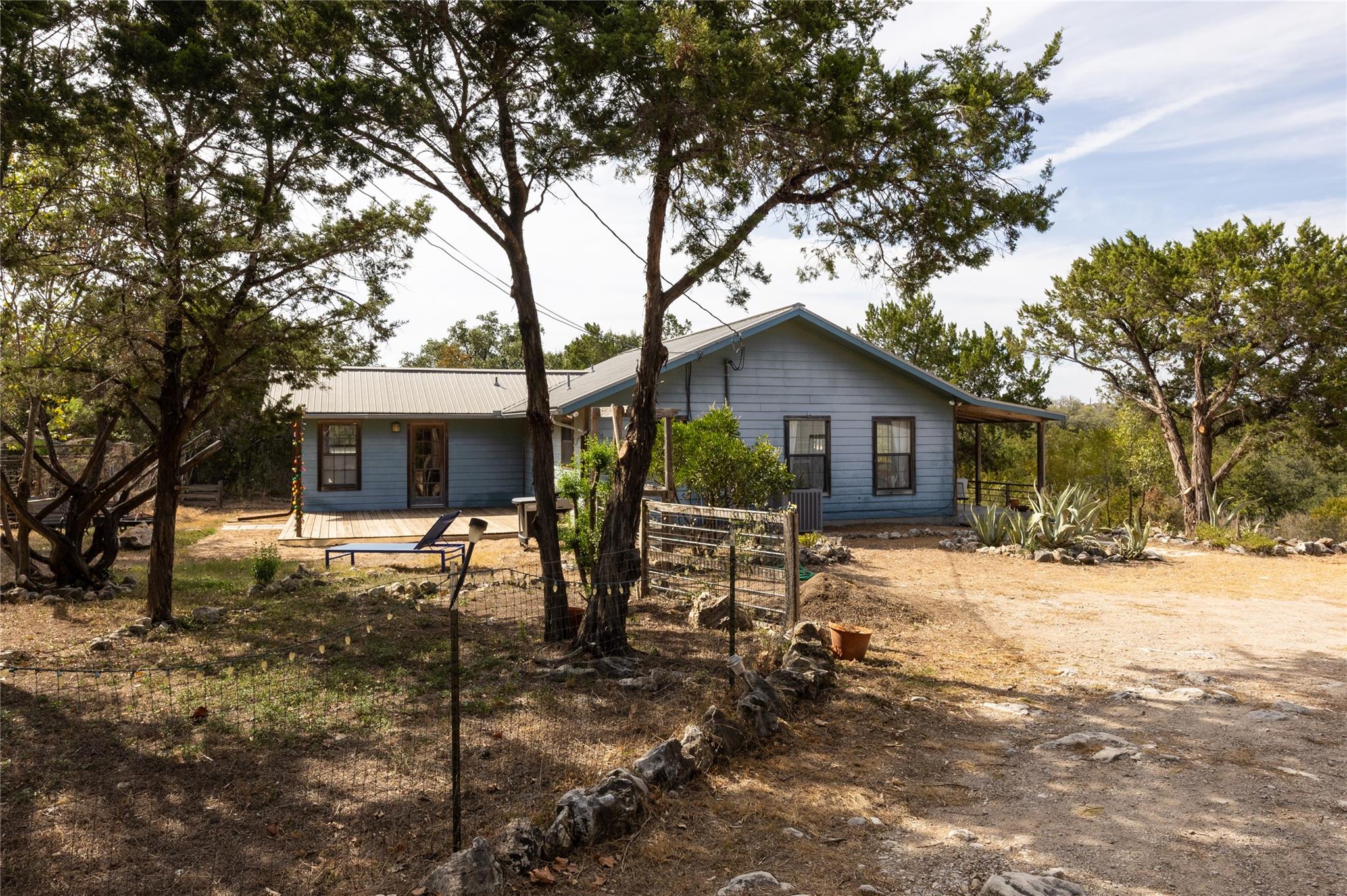 Mature trees frame a charming metal-roofed home n