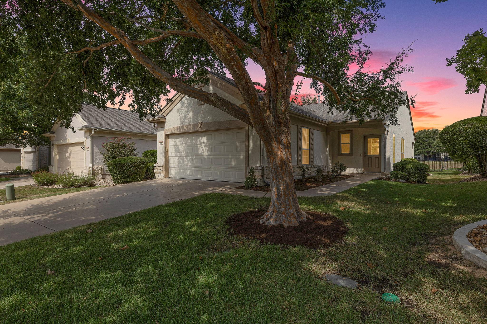 Mature trees shade the manicured front lawn leadi