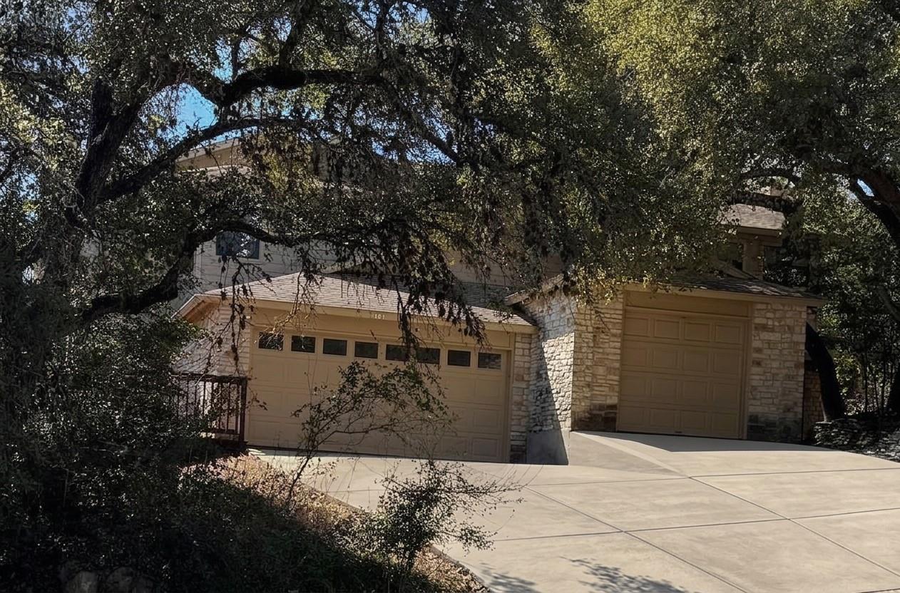 Mature trees shade a spacious concrete driveway l