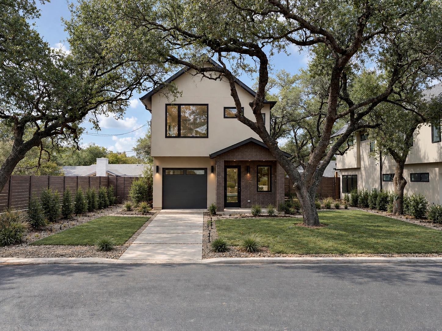 Mature oak trees frame a modern facade with stucc